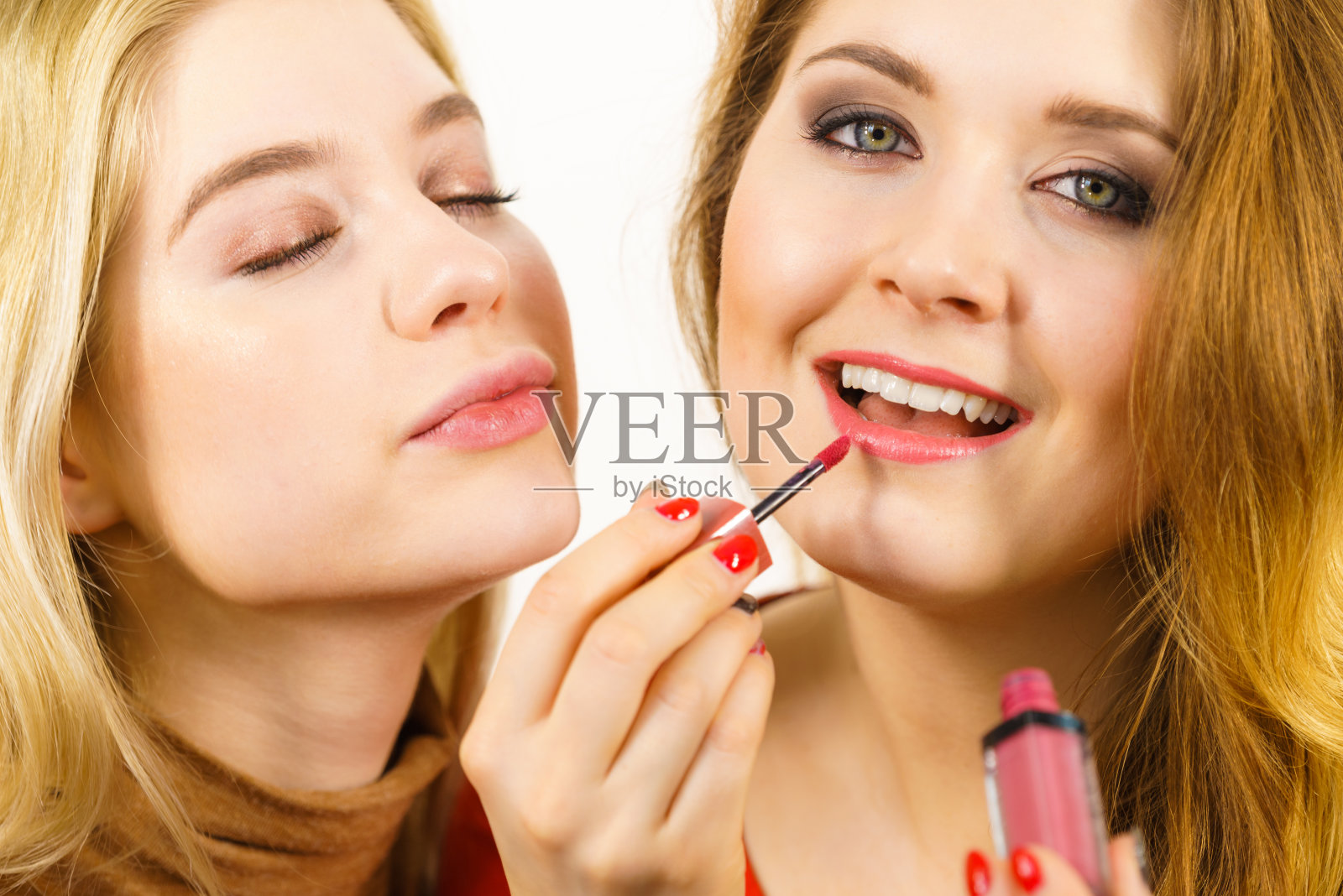 一个女人给她的朋友涂口红照片摄影图片