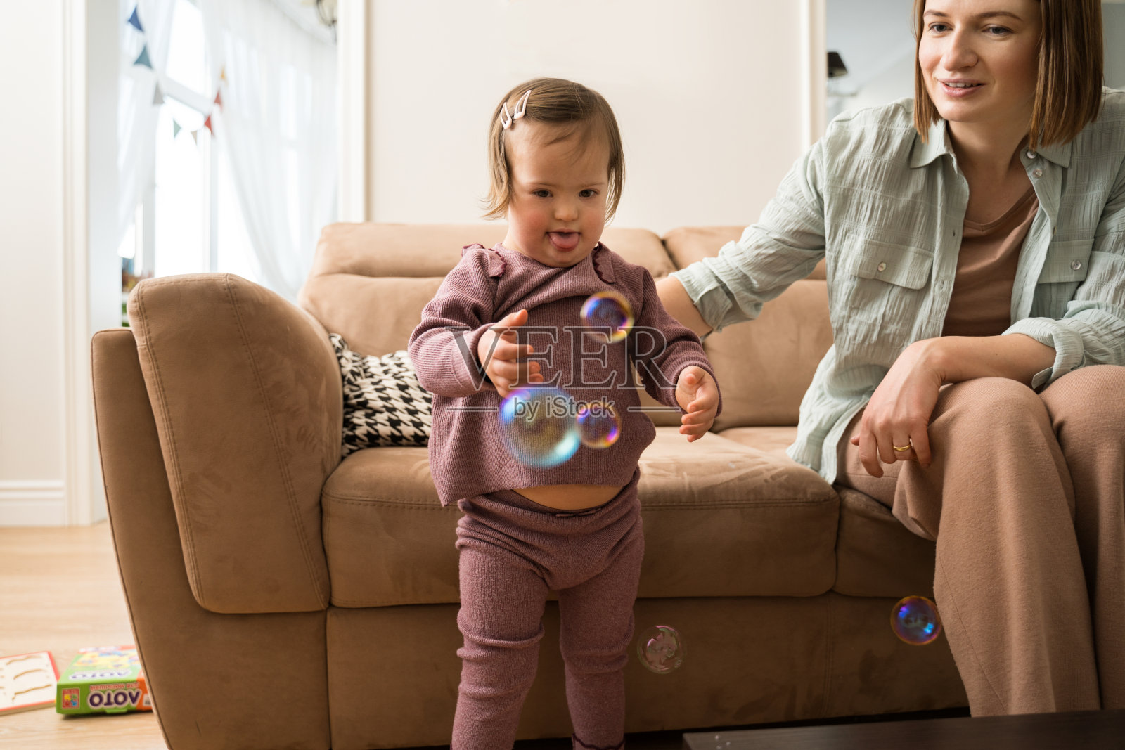 妈妈坐在沙发上和女儿一起玩肥皂泡照片摄影图片