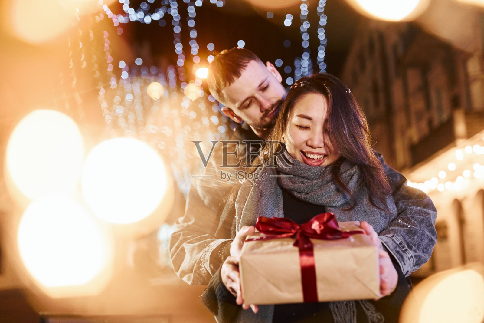 礼物盒。幸福的多种族夫妇一起在城市户外庆祝新年照片摄影图片
