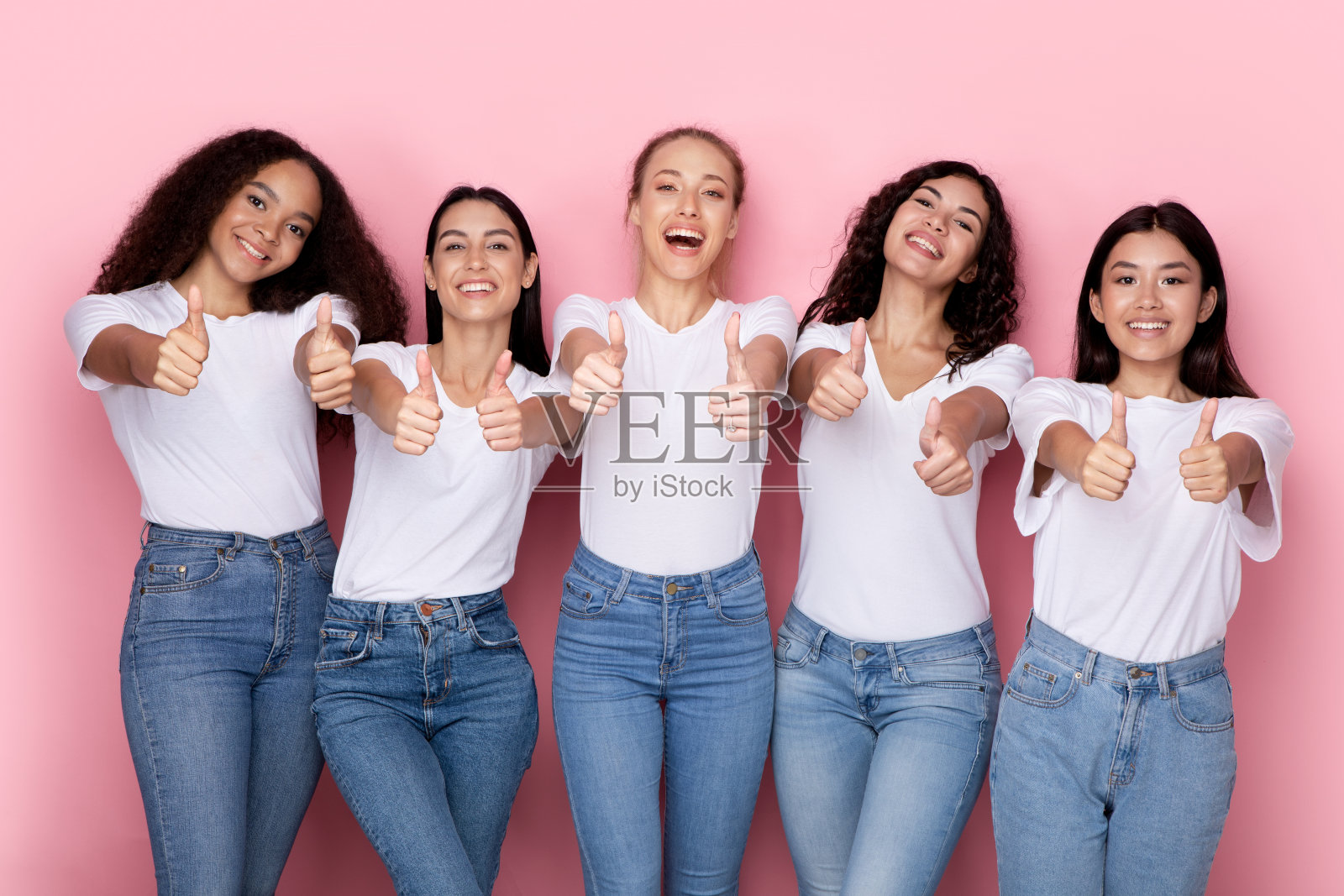 多种族女性用双手做出类似的手势，粉色背景照片摄影图片