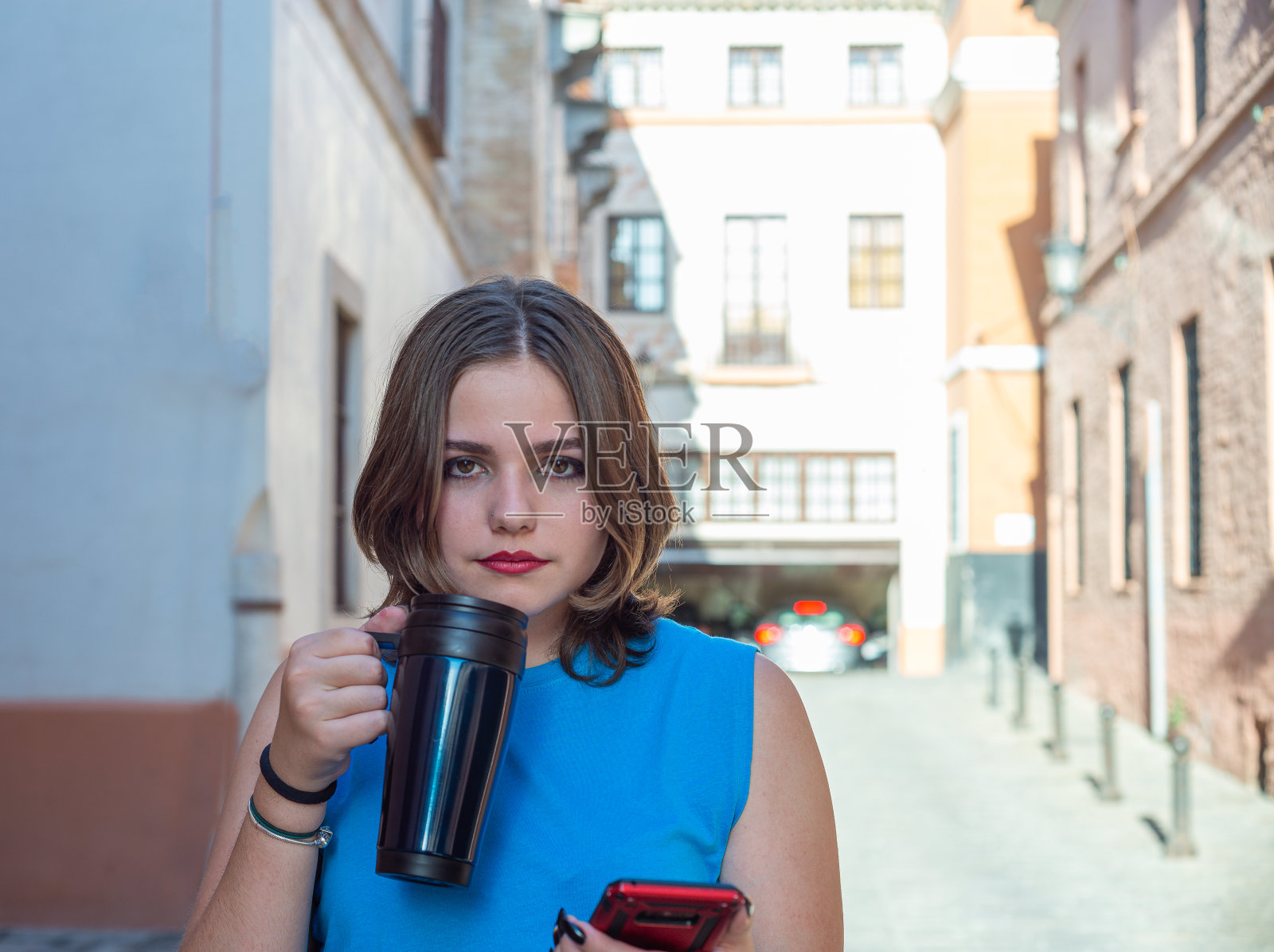 年轻女子短发，走在街上，边喝咖啡边打电话照片摄影图片