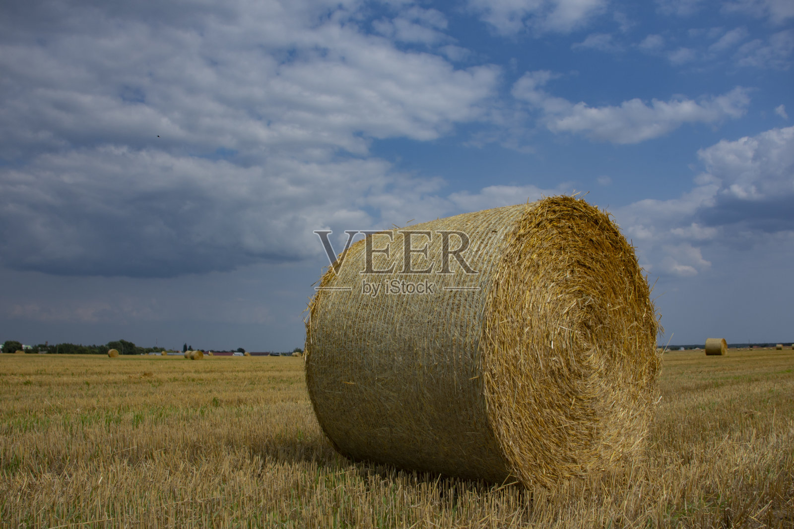 夏天从田野里收集的干草堆，以天空的云朵为背景。照片摄影图片