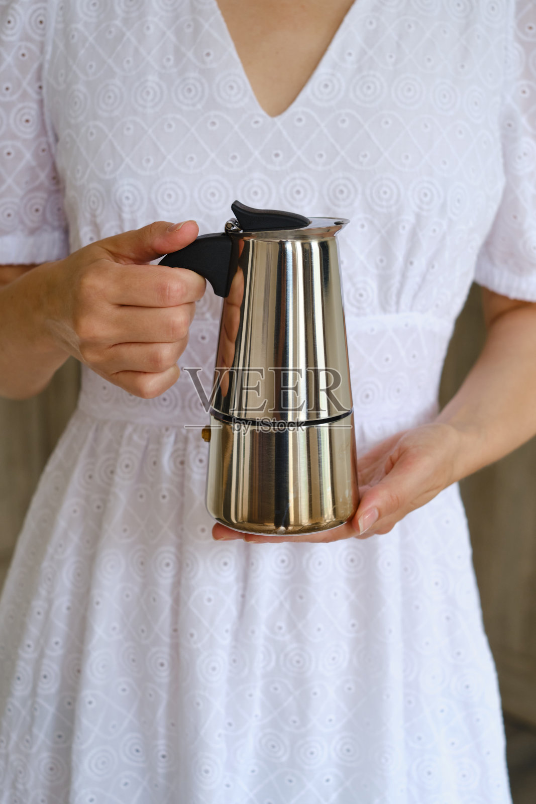 一个女孩手里拿着一个摩卡壶，用来煮新鲜的热咖啡。金属咖啡壶的特写镜头。煮咖啡的设备。专业的咖啡酿造照片摄影图片