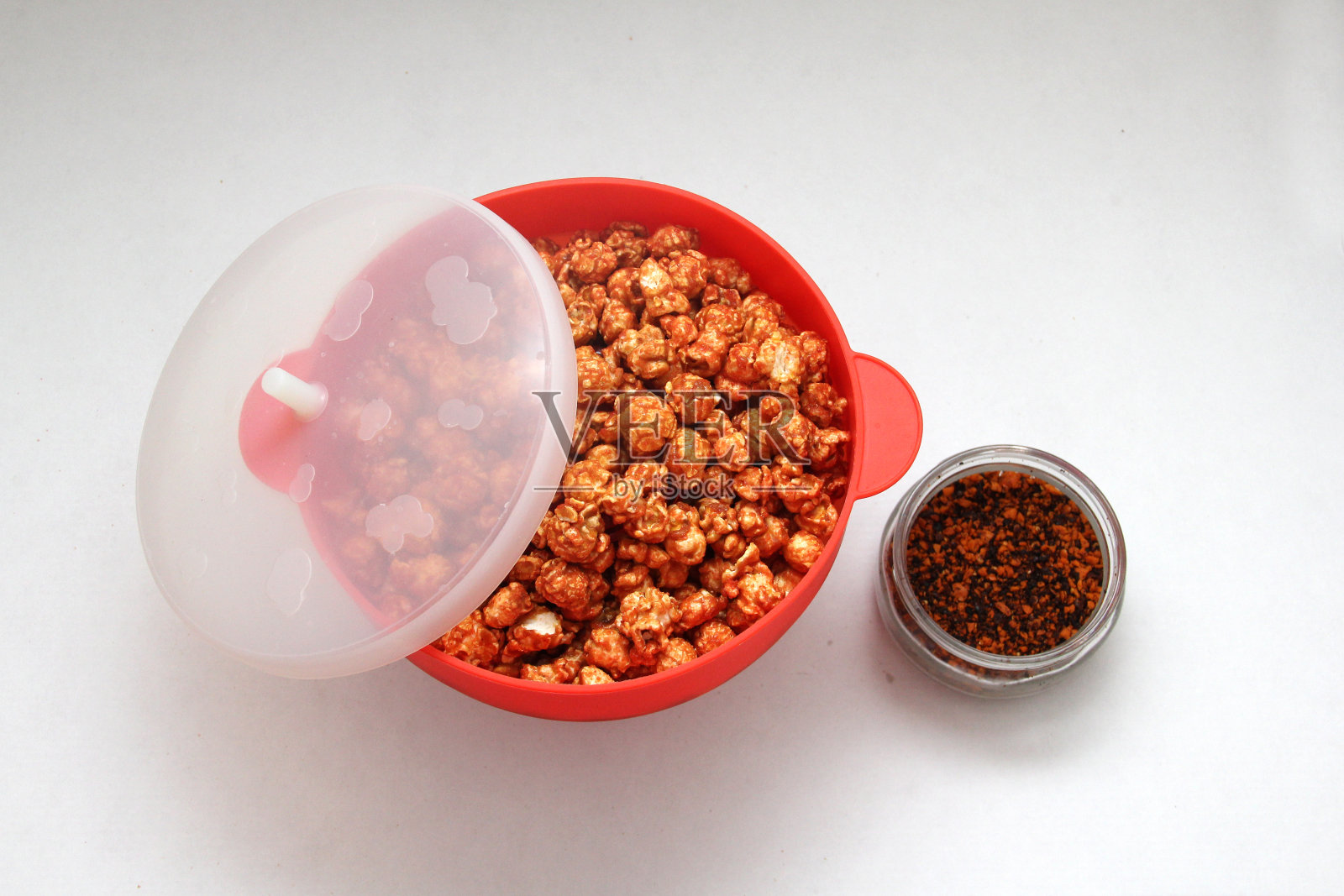 红辣椒覆盖的爆米花在红色微波容器照片摄影图片