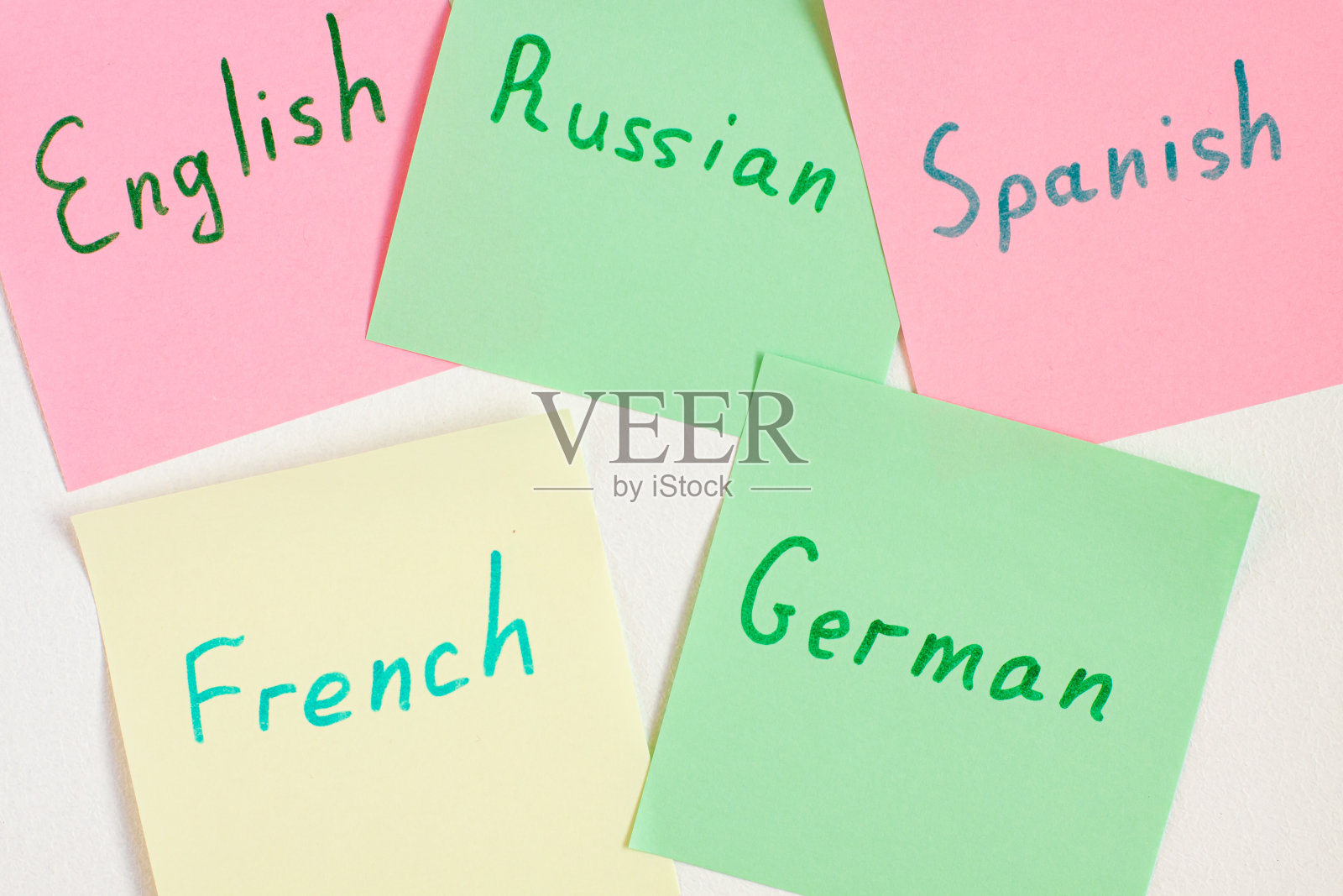 俯视图平铺不同的语言，写在不同颜色的提醒纸上。抽认卡和语言学习概念概念。德语，英语，西班牙语，法语和俄语照片摄影图片