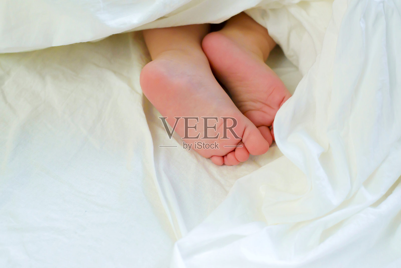 床上熟睡的婴儿的脚很可爱。照片摄影图片
