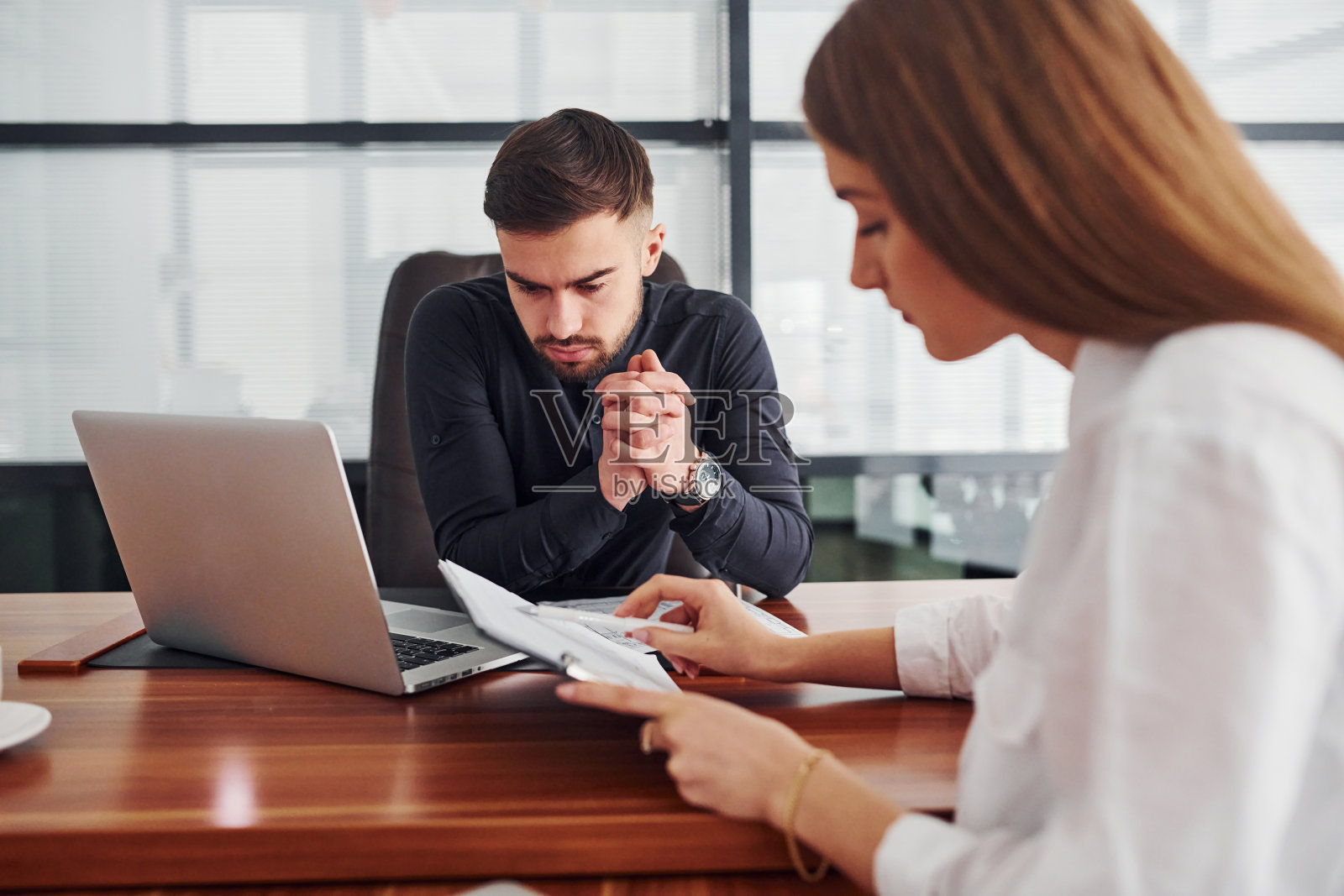 男女穿着正装一起在办公室室内的桌子旁工作，拿着文件照片摄影图片