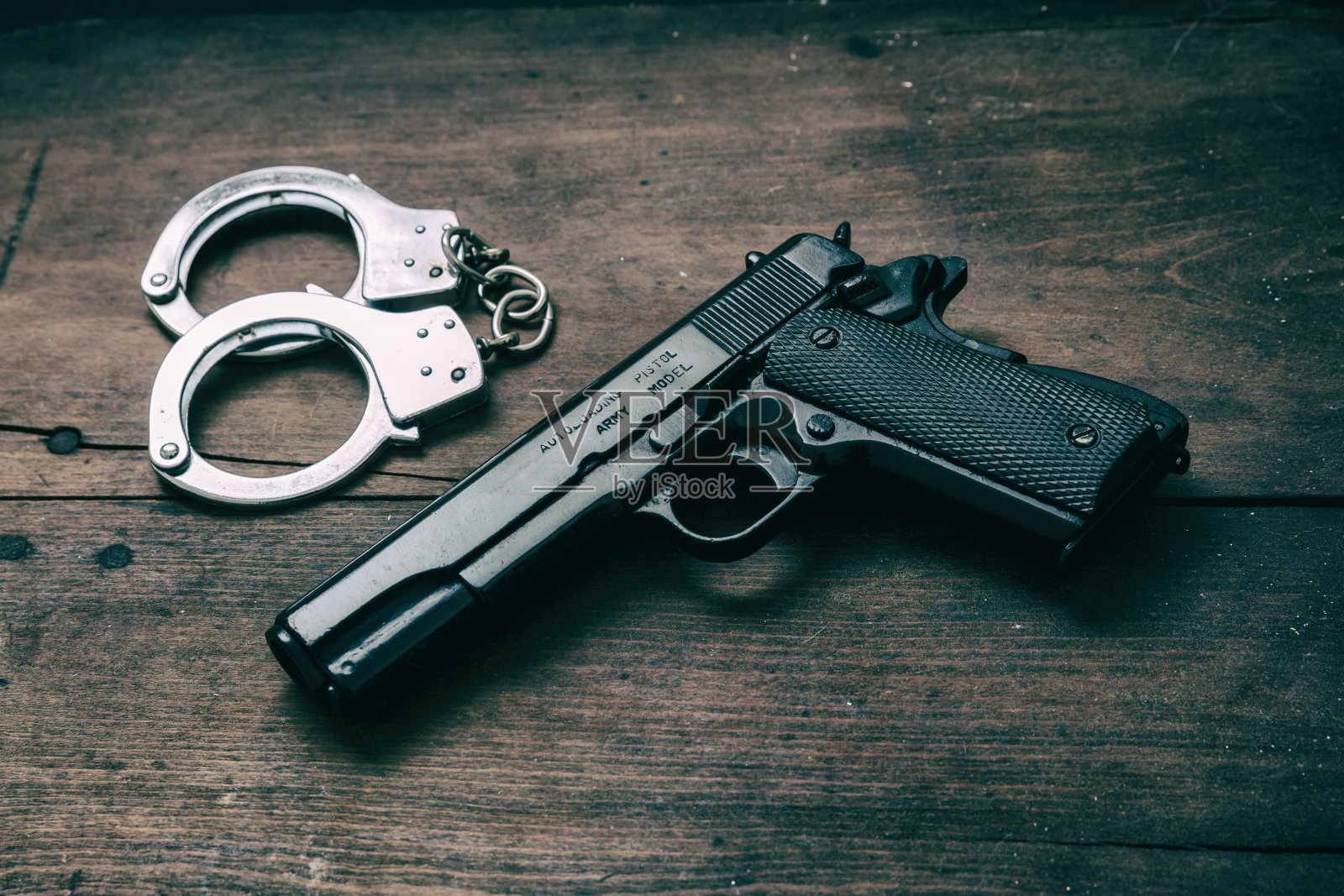 9毫米手枪，木桌上有手铐。汽车金属武器侧面视图照片摄影图片
