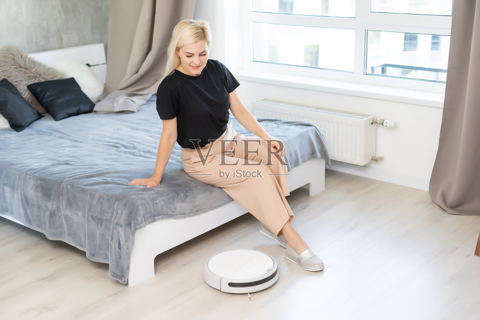 年轻女子用自动吸尘器打扫地板，操控机器家务机器人照片摄影图片