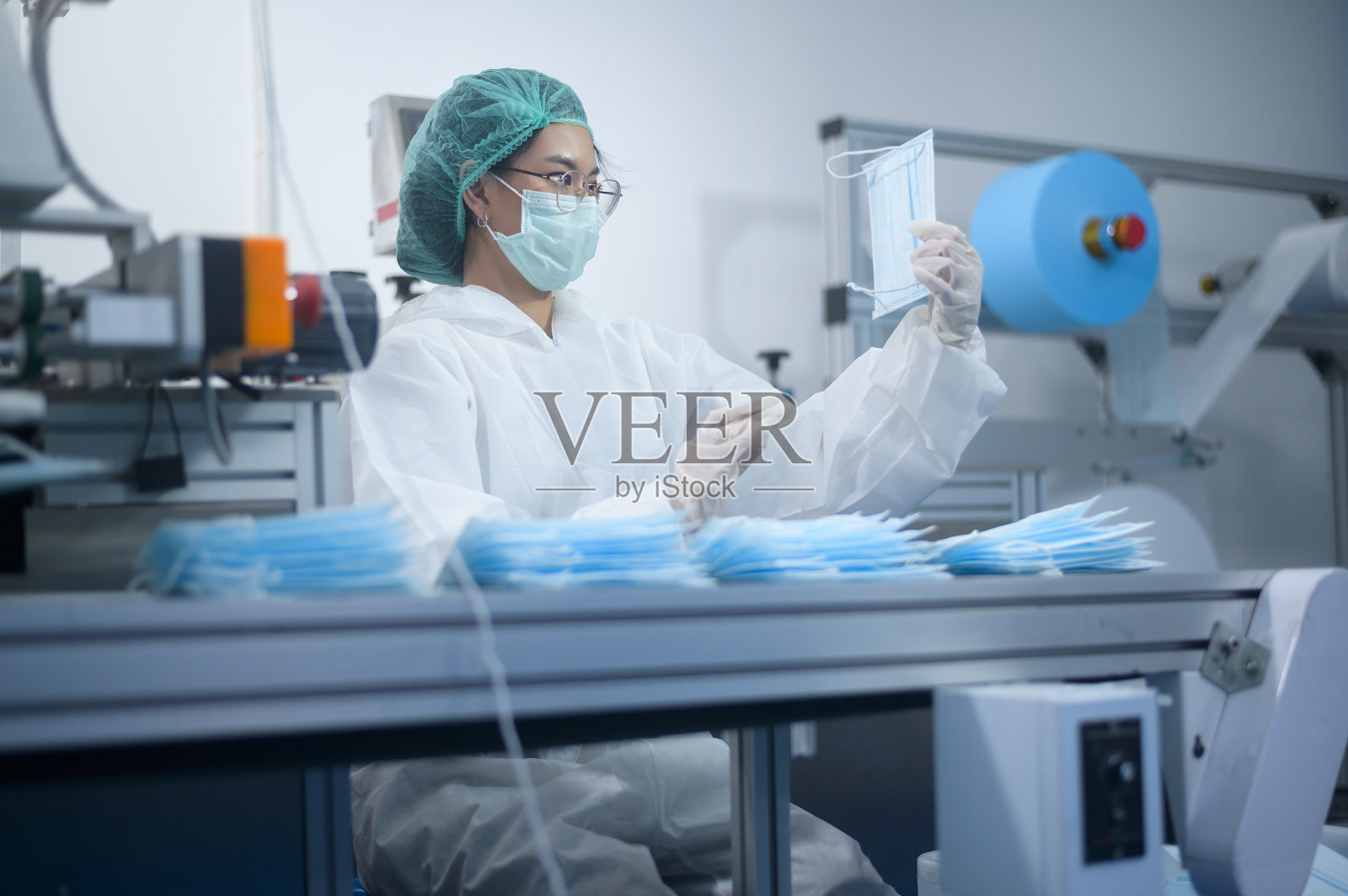 现代工厂生产外科口罩的工人，新冠病毒防护和医疗理念。照片摄影图片