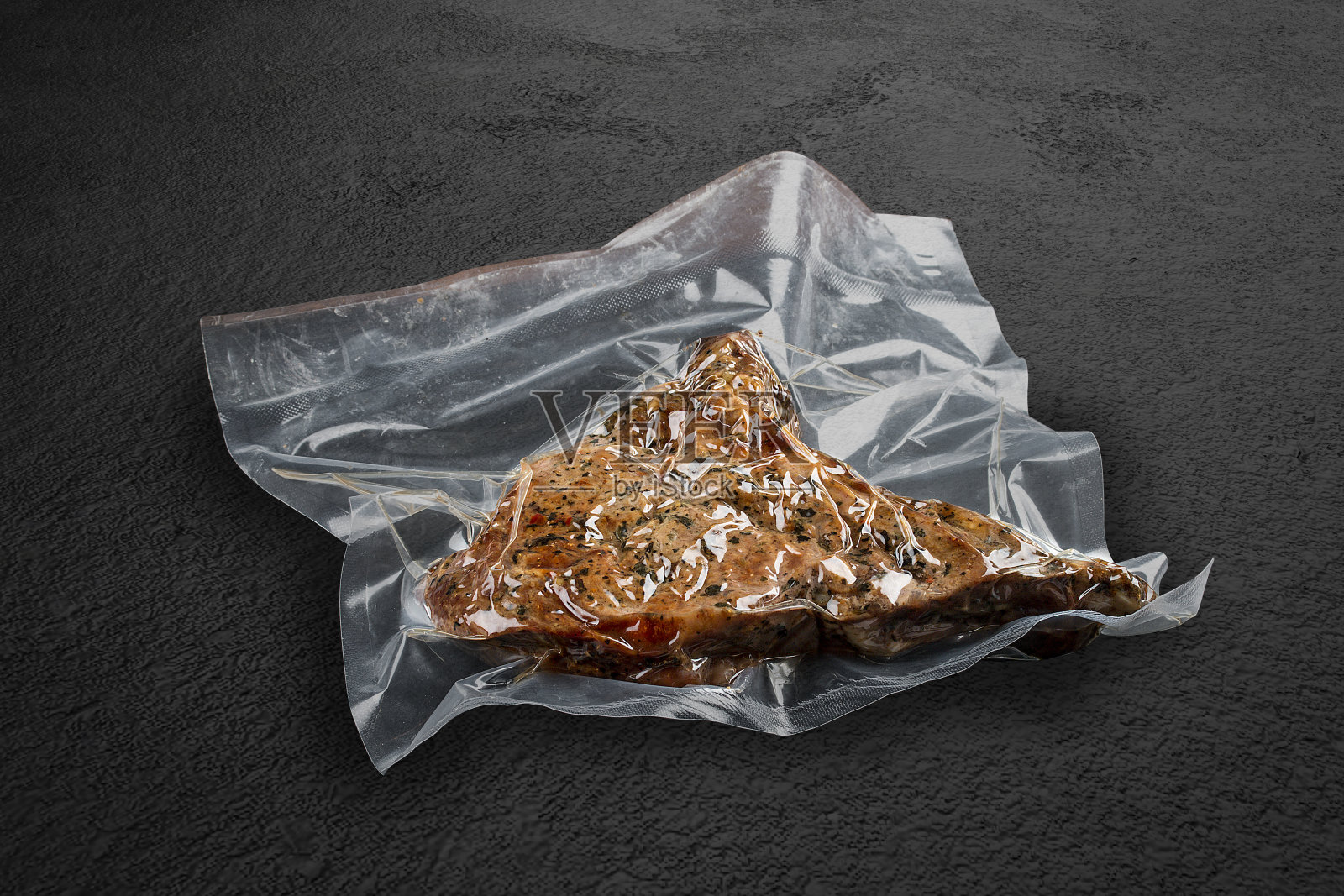 真空包装的烤肉，深色背景，小牛肉。可以吃了。照片摄影图片