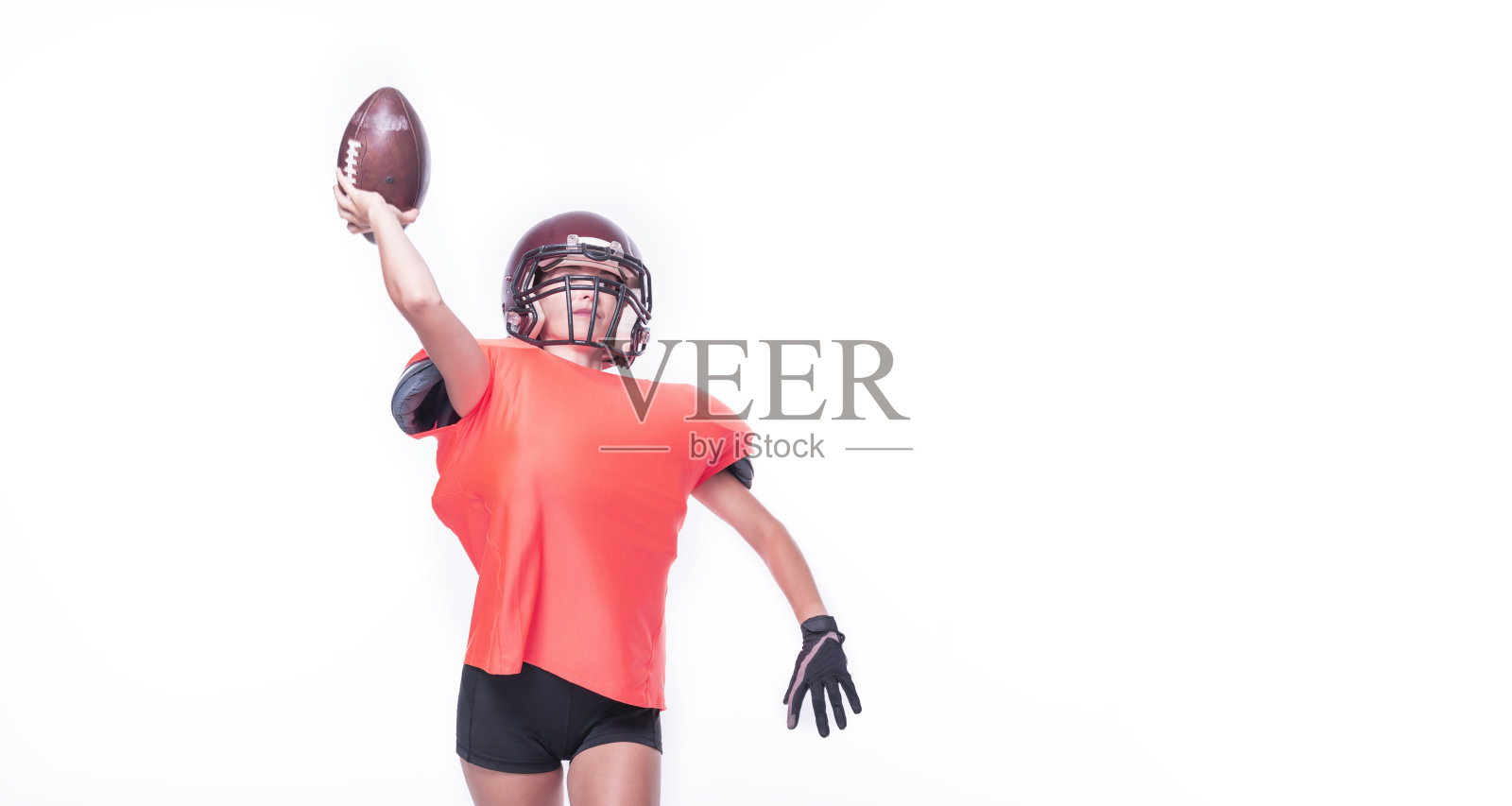 身穿美式橄榄球队队服的女人正在扔球。运动概念。照片摄影图片