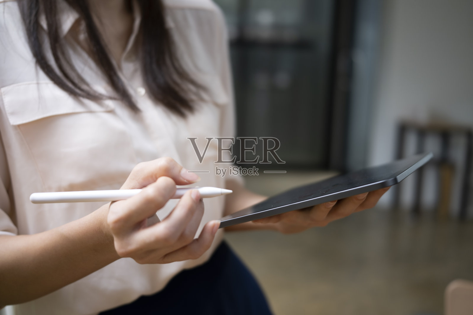 照片中的女人手里拿着电子平板电脑和手写笔。照片摄影图片