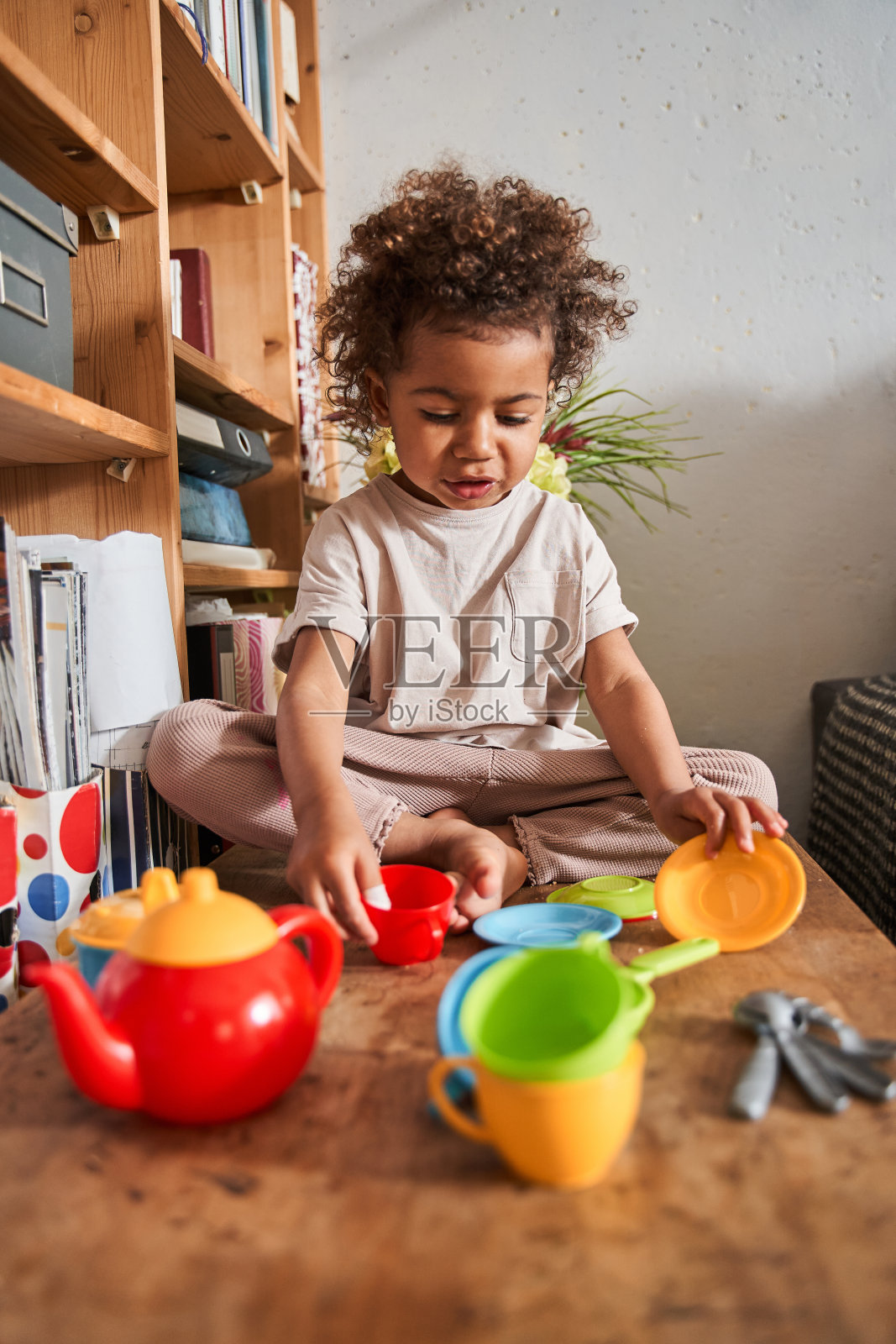 女孩坐在桌旁，看着她的玩具，同时准备玩照片摄影图片