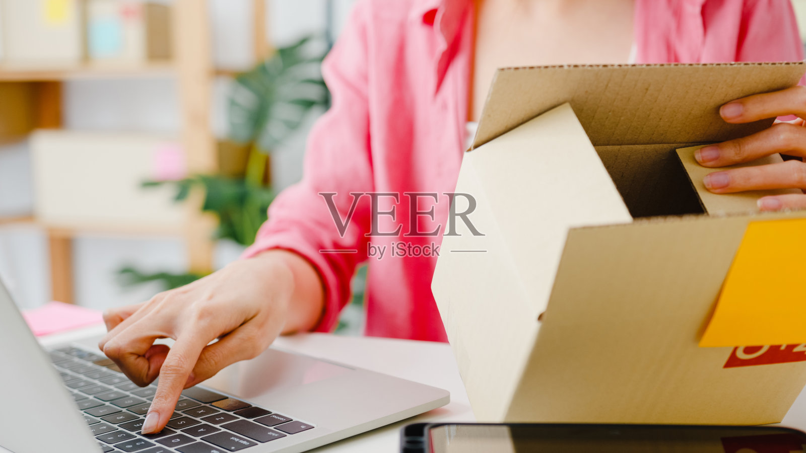 年轻的亚洲企业家女商人检查产品采购订单上的库存，并保存到电脑笔记本电脑工作在家里的办公室。照片摄影图片