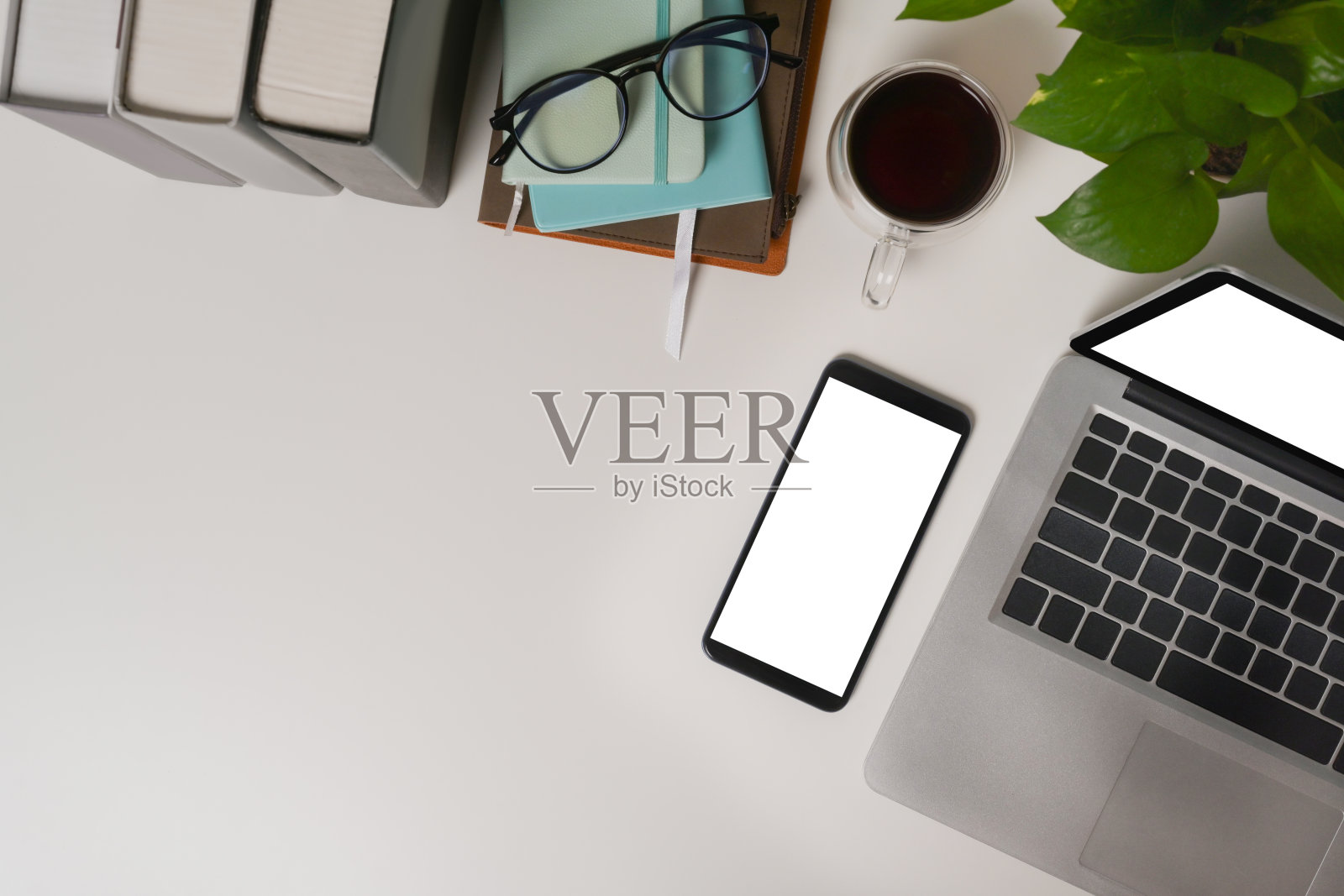 上面的观点办公室书桌与手机，笔记本电脑和室内植物。照片摄影图片