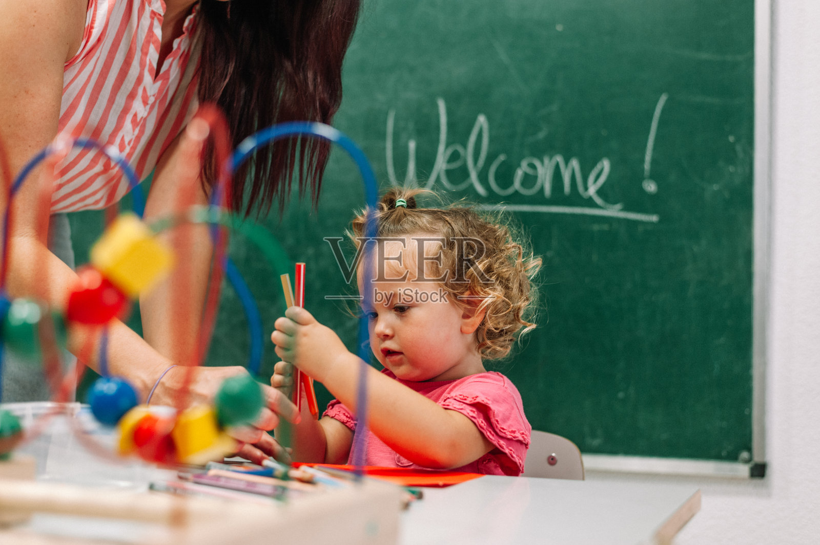 老师和学步的小女孩在幼儿园用彩色铅笔画画照片照片摄影图片