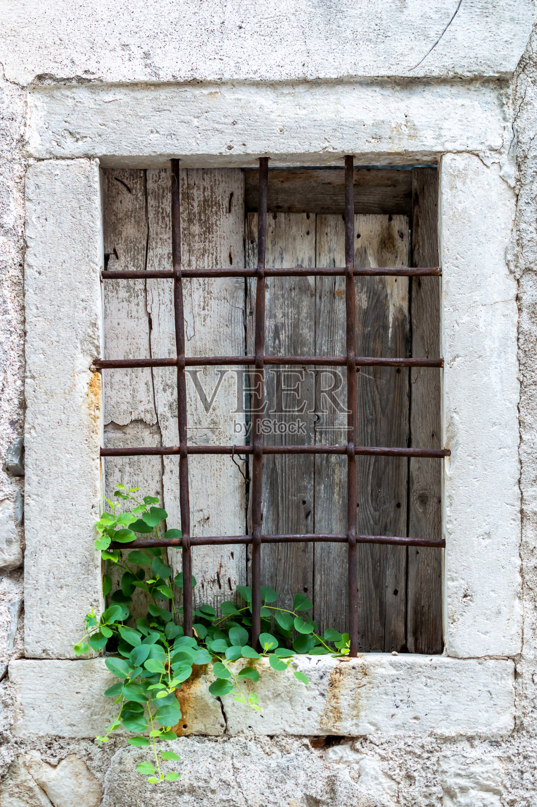 老石墙上有生锈的窗。照片摄影图片