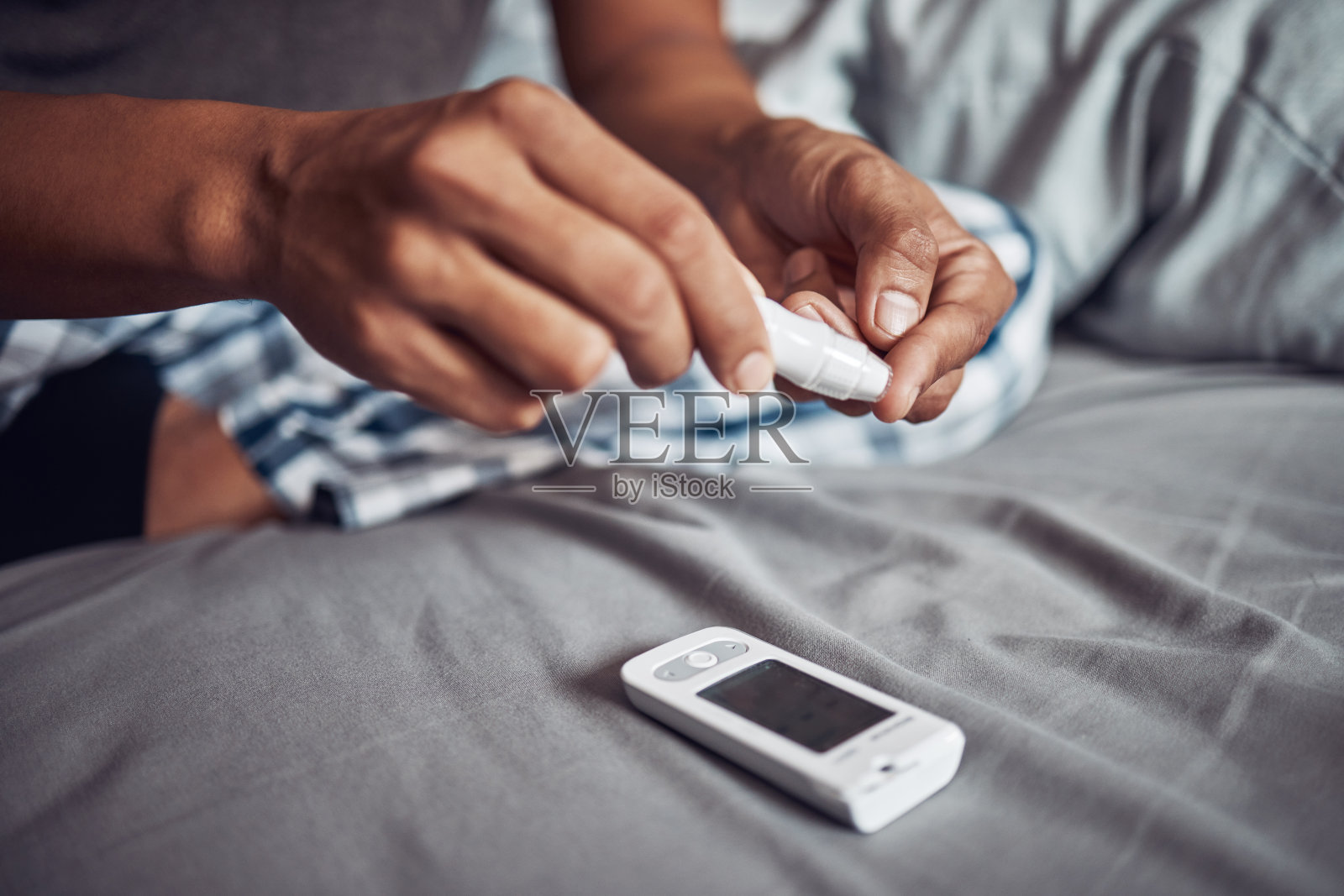 一个完全不认识的男人在家里的床上用手指测血糖照片摄影图片