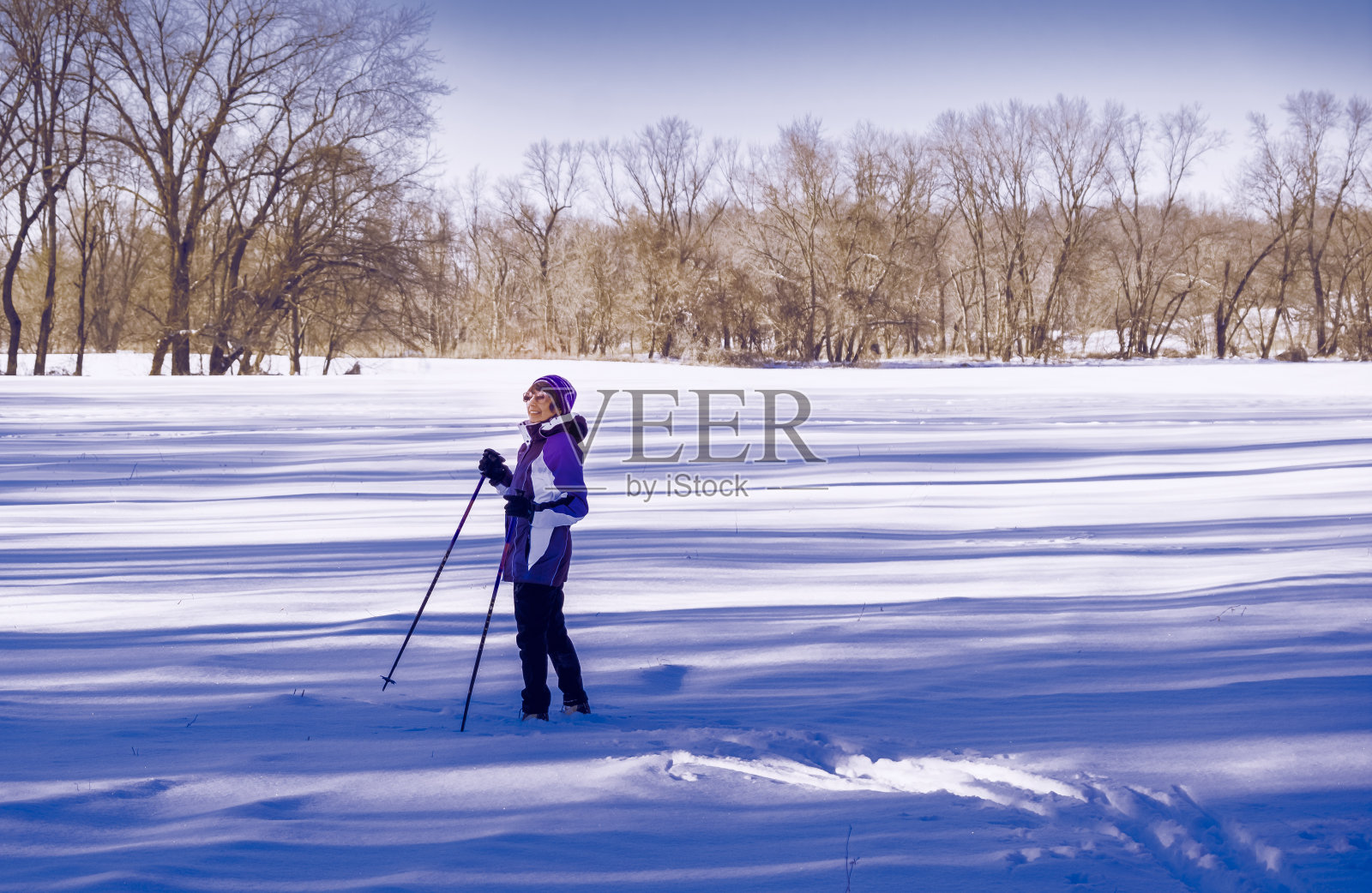 在中西部，一名成熟的女子越野滑雪爱好者正在享受午后的新鲜雪照片摄影图片