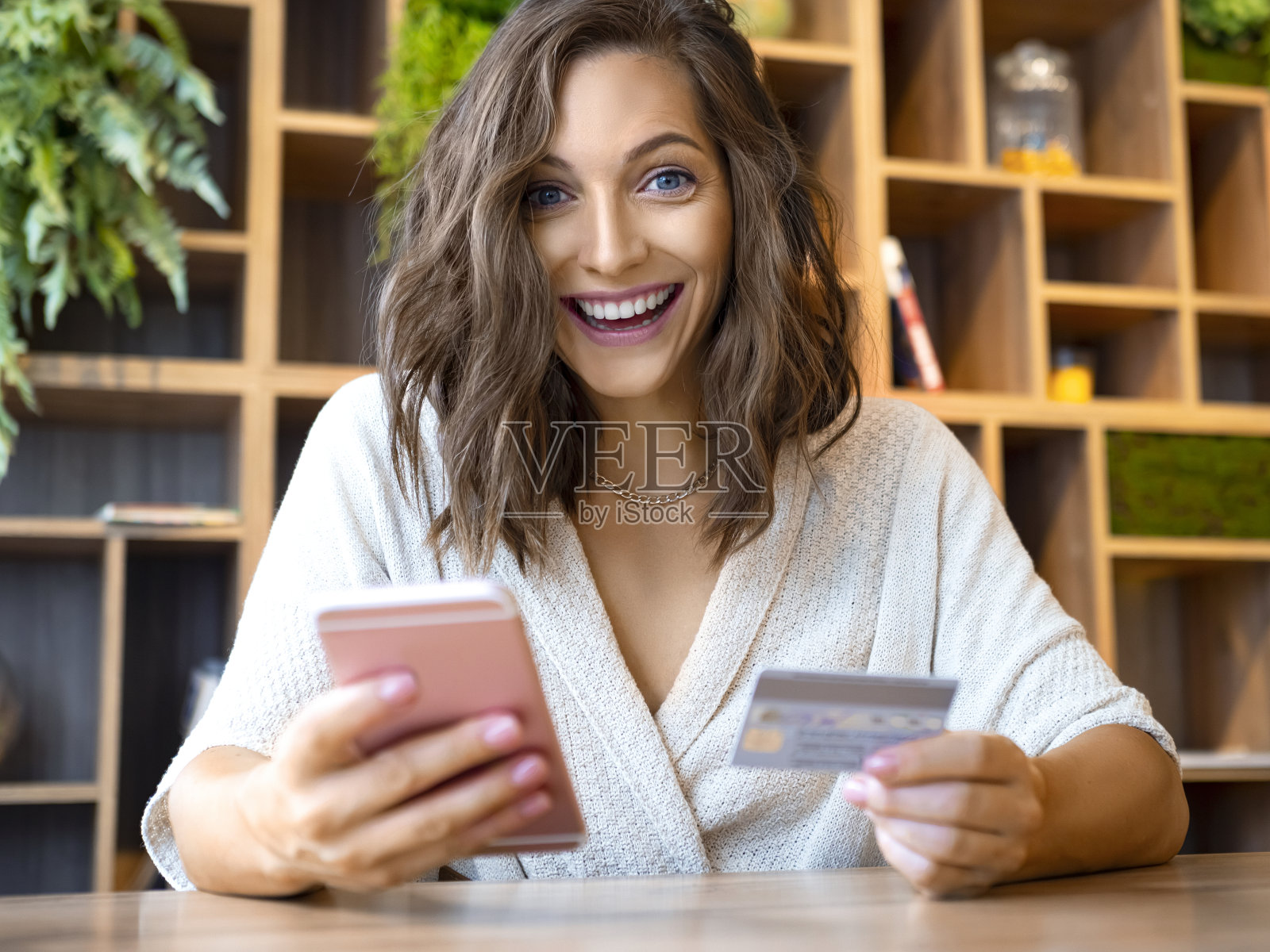 一名年轻女子的肖像，带着智能手机和信用卡。她开心地笑着，看着镜头照片摄影图片