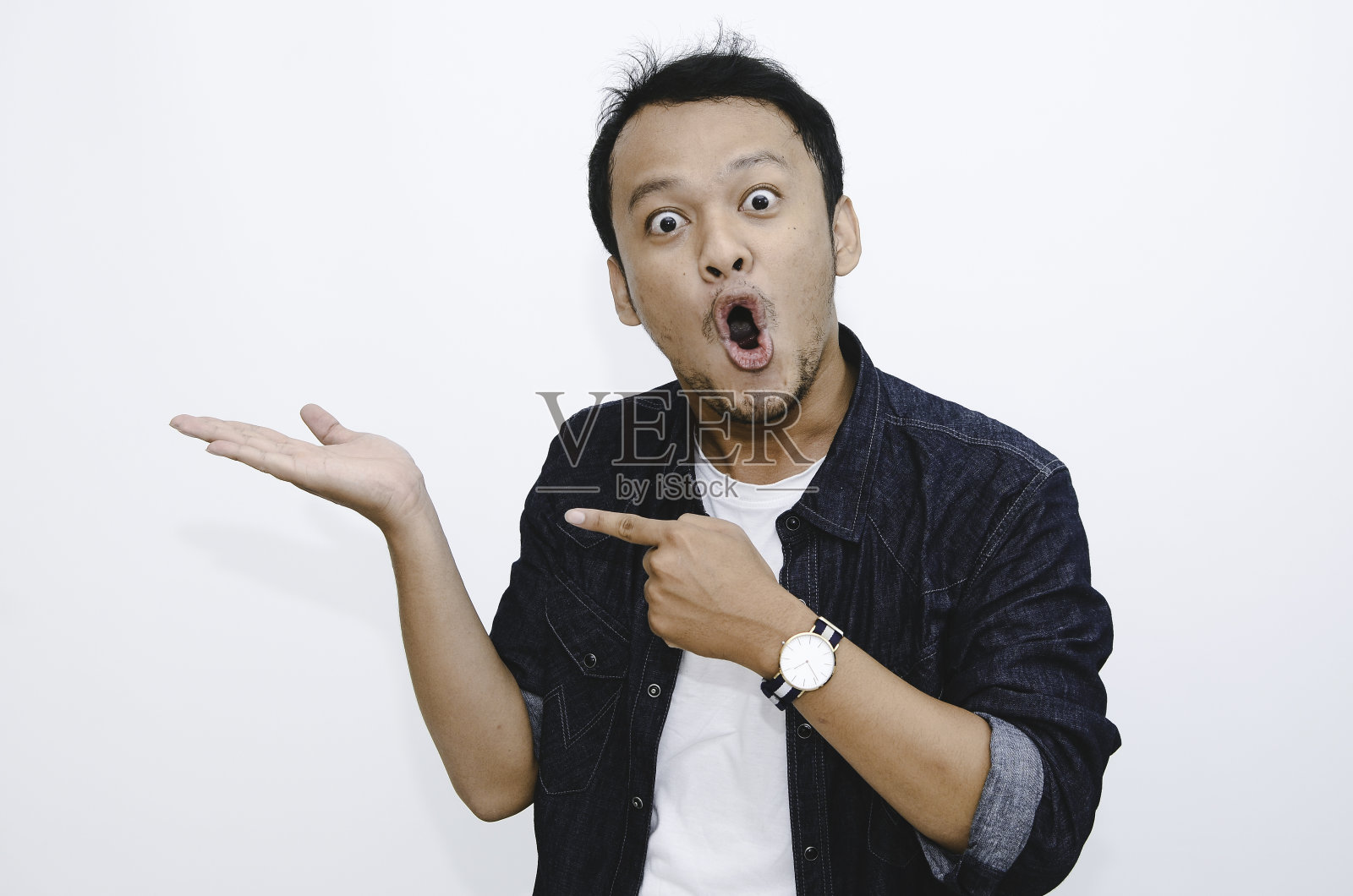 年轻的亚洲男子惊讶地大叫哇，用他孤立在灰色背景上的手指向右边。照片摄影图片