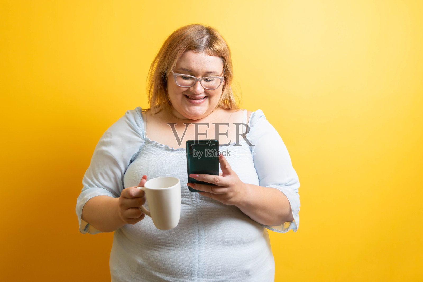 美丽和快乐的年轻白人胖女人微笑着喝咖啡和手机。超重的人照片摄影图片