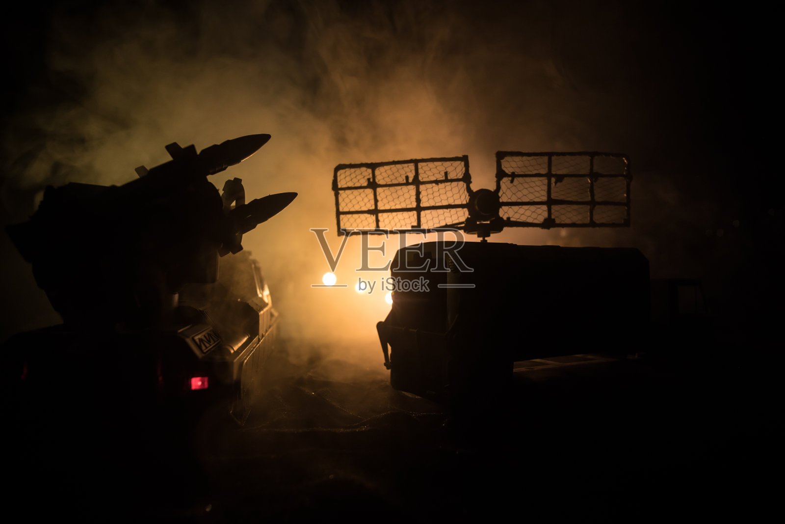 创意艺术品装饰。日落时带有雷达天线的机动防空卡车剪影。傍晚天空下的卫星天线或无线电天线。照片摄影图片