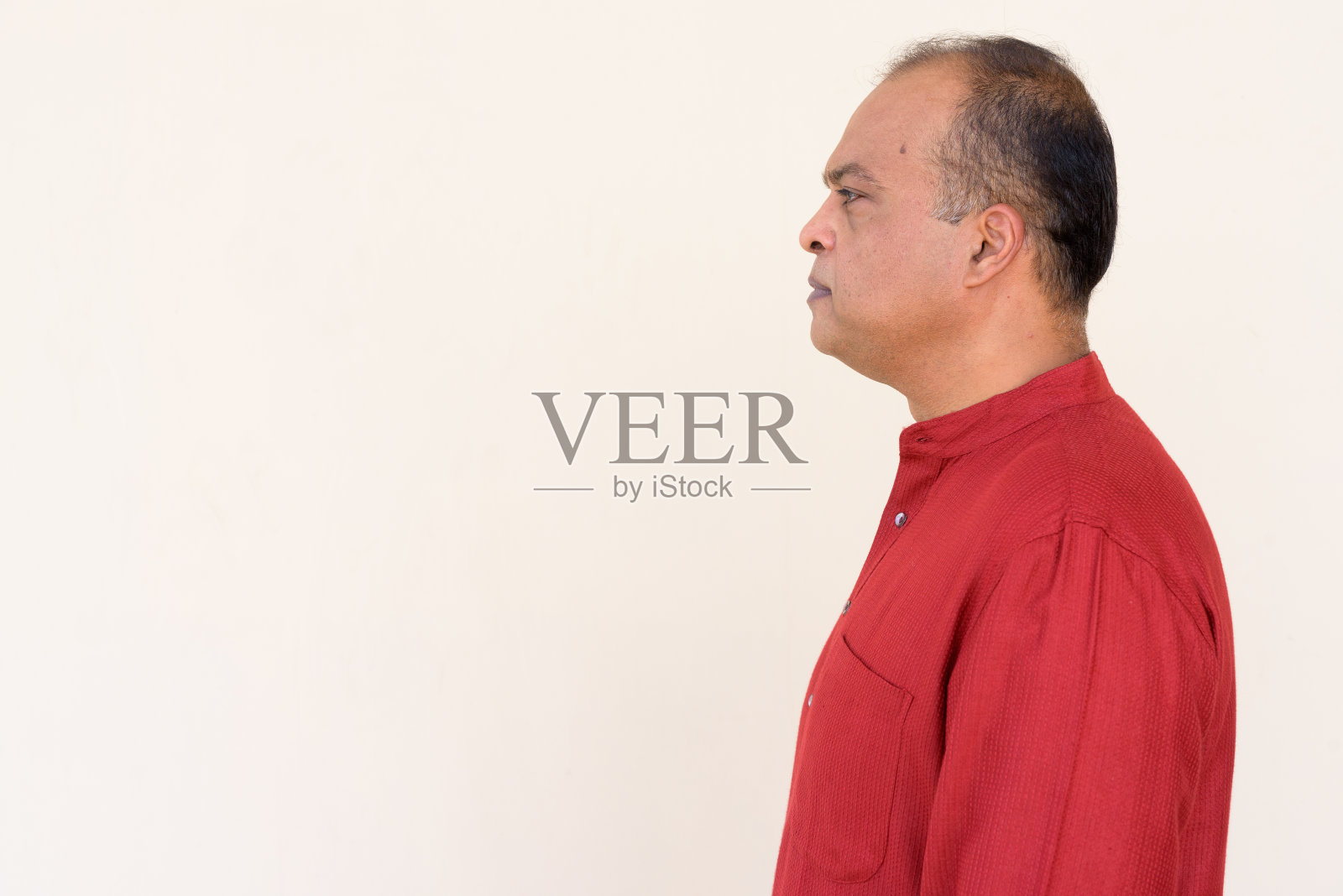 印度男子的侧面视图，穿着传统的衣服，对着朴素的墙壁在户外照片摄影图片