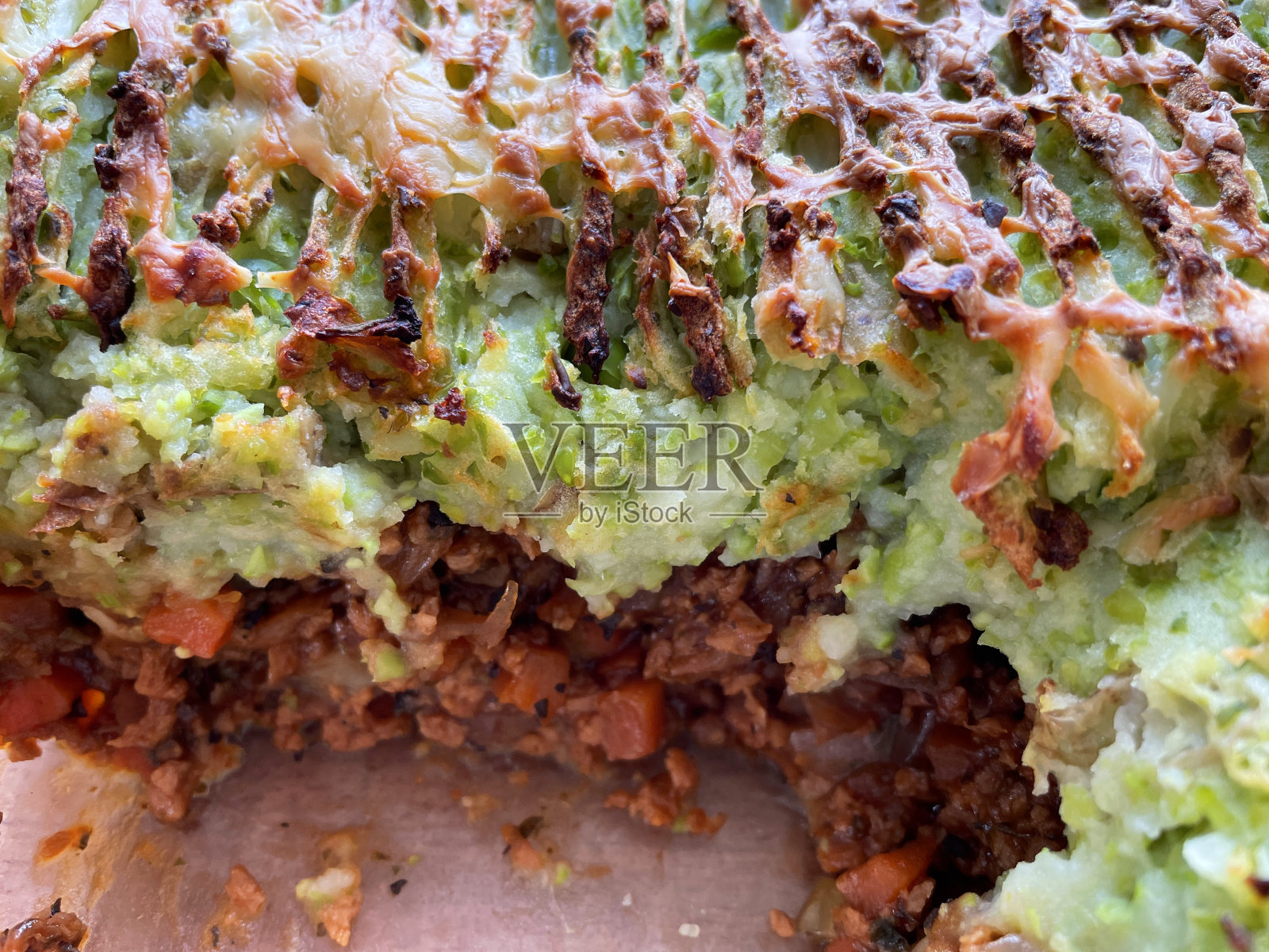 全帧图像自制的英国农舍/牧羊人派与切碎的牛肉/羊肉在玻璃防烤箱盘，青豆和马铃薯泥与叉形图案，缺失的部分，高架视野，聚焦前景照片摄影图片