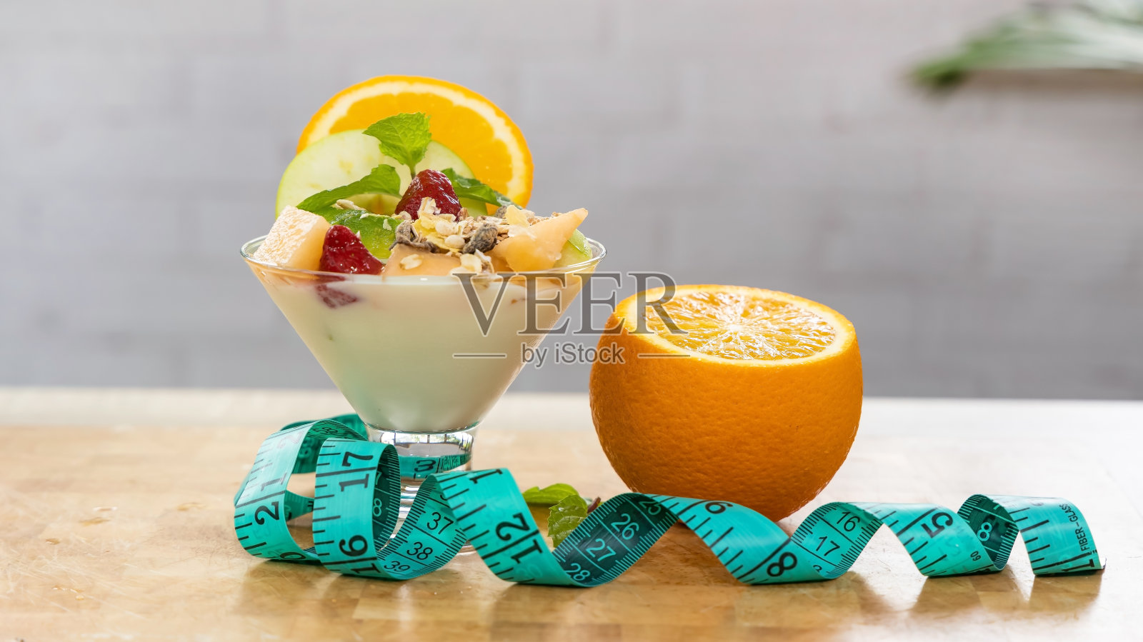 在厨房的背景下，用一杯格兰诺拉麦片冻糕吃健康的酸奶和橘子照片摄影图片