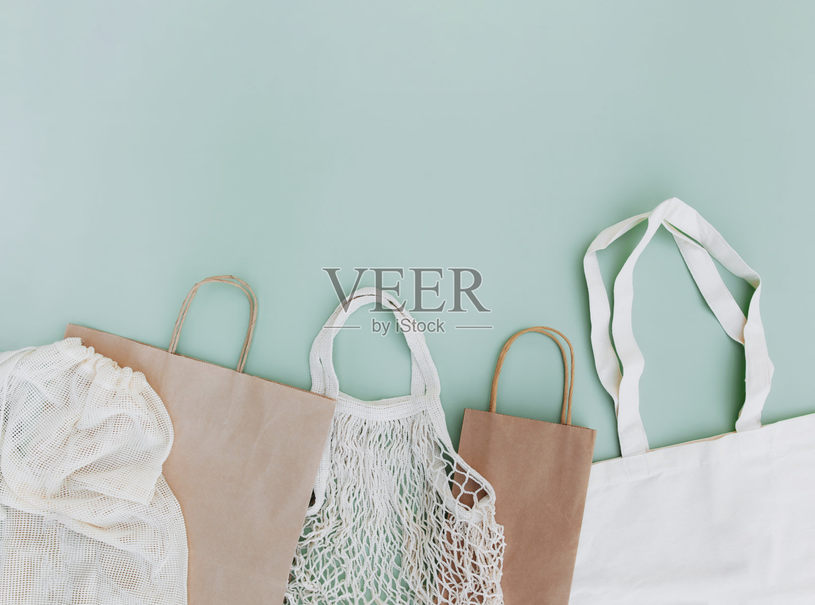 绿色背景上平铺着环保纸和网袋照片摄影图片