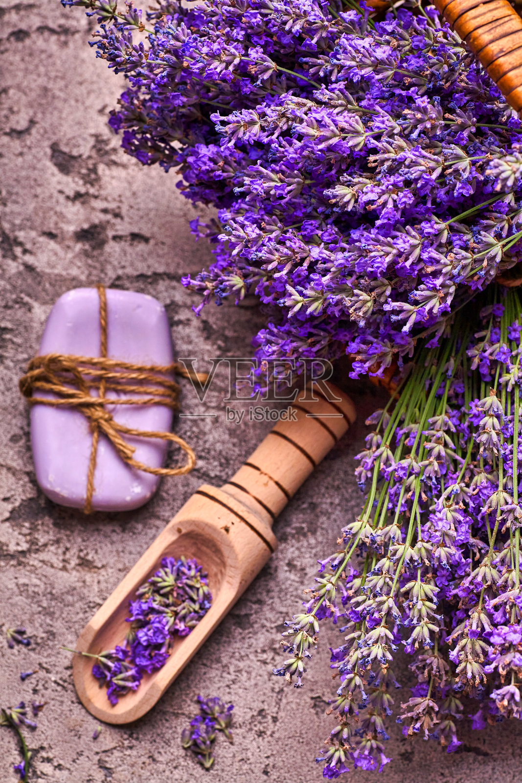 篮子里有薰衣草花，灰色混凝土背景上有芳香的肥皂。前视图。照片摄影图片
