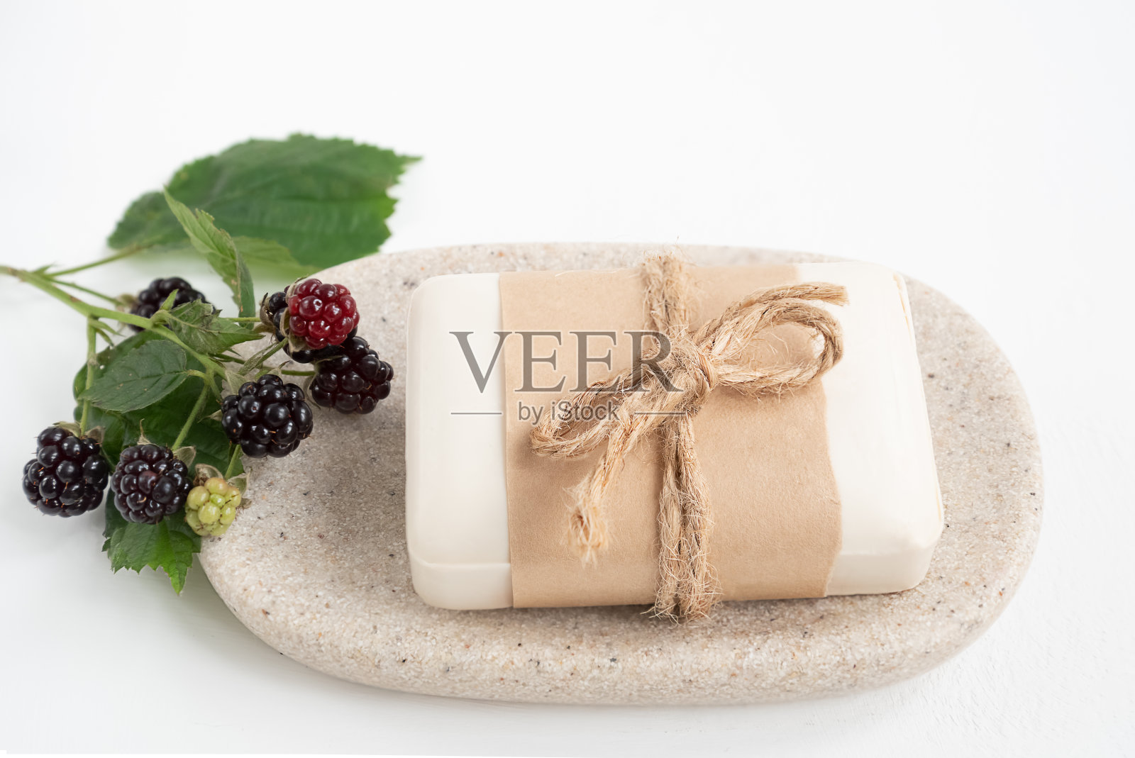 一块有机肥皂包裹在牛皮纸托盘新鲜的黑莓枝照片摄影图片