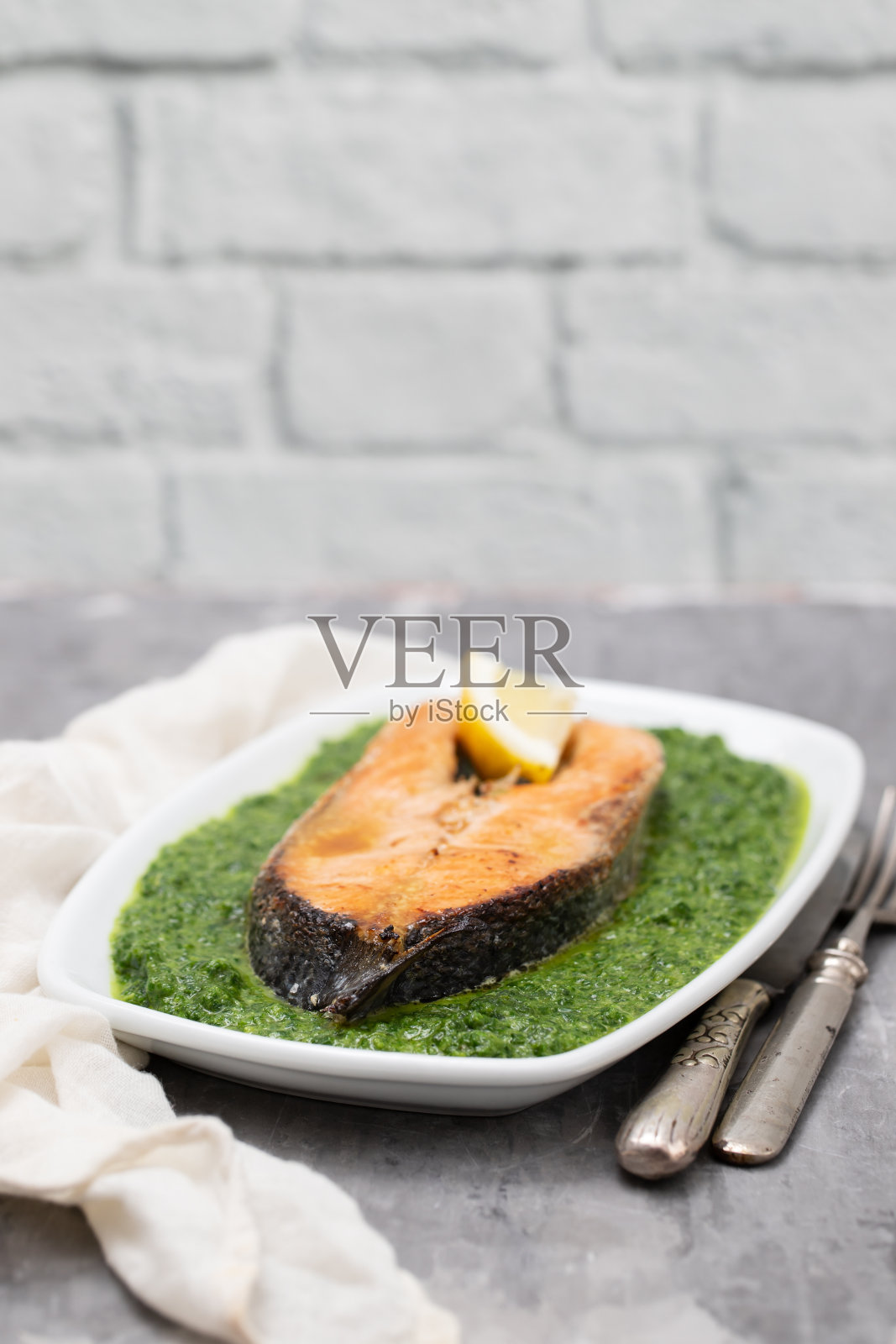 新鲜柠檬和菠菜煎鲑鱼放在白色的盘子里照片摄影图片