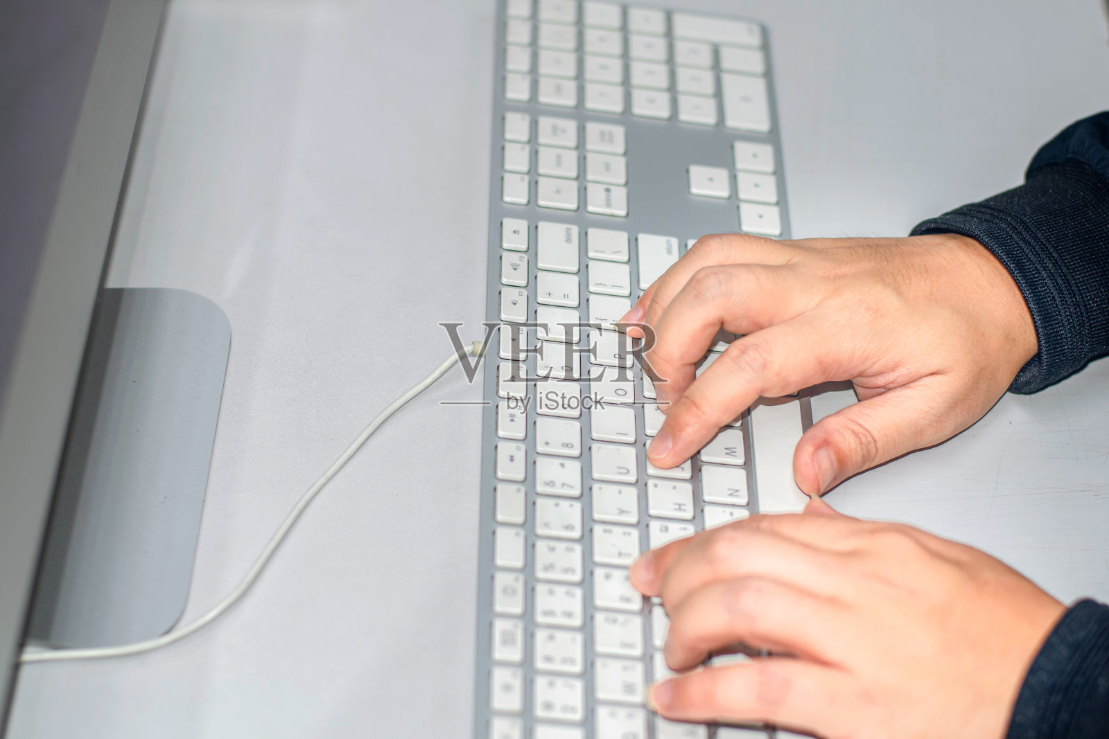 一个年轻人正在用他的双手在电脑键盘上打字。照片摄影图片