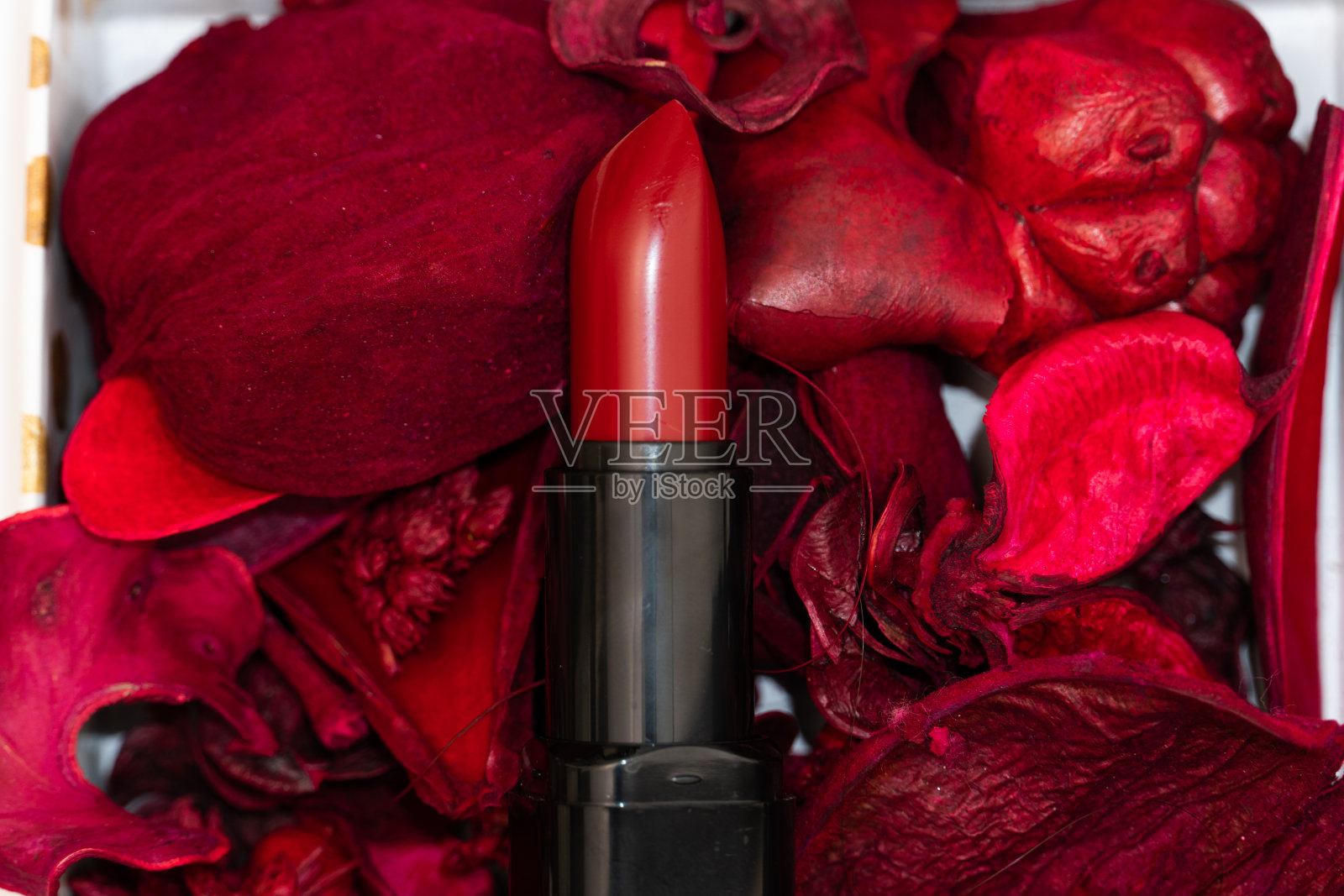 红色口红化妆品的背景是装饰性的花瓣照片摄影图片