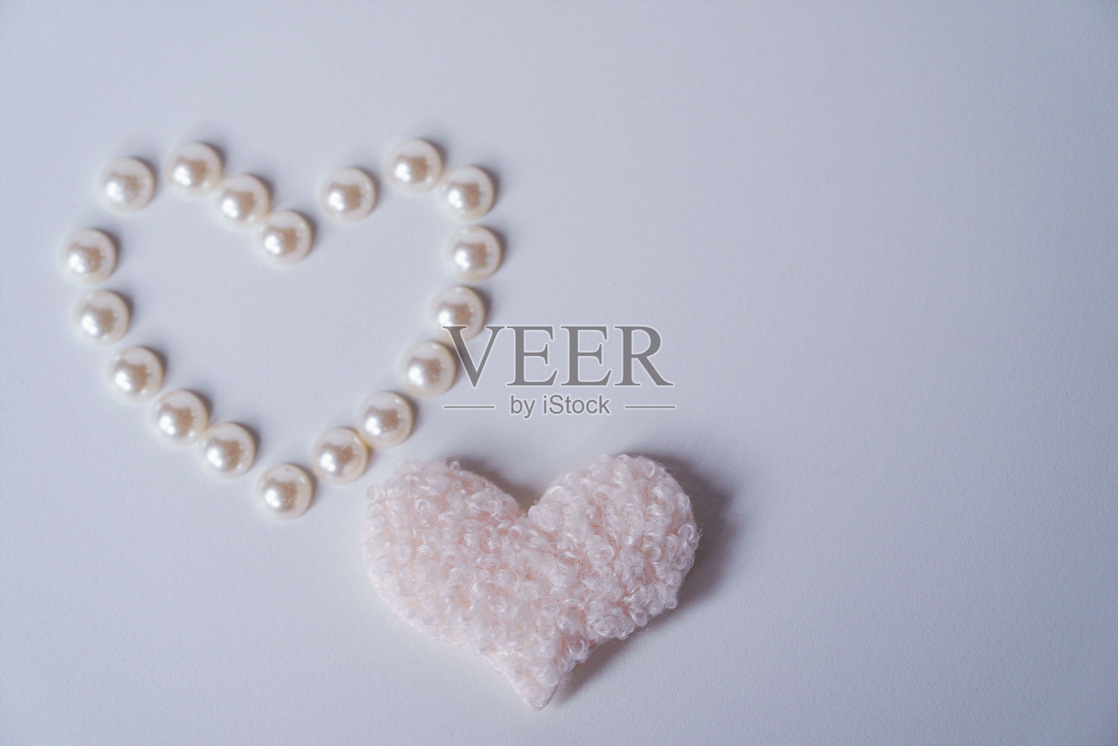 精致的米色绒毛心和珍珠在白色背景。爱的概念。情人节快乐。小女孩一岁生日贺卡。照片摄影图片