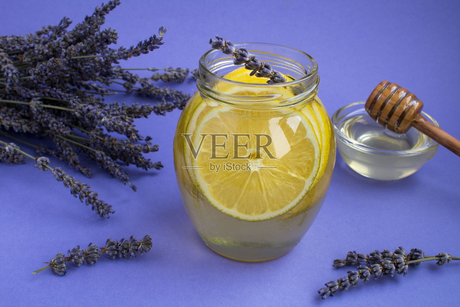 蜂蜜、柠檬和薰衣草放在紫色背景的玻璃罐里照片摄影图片
