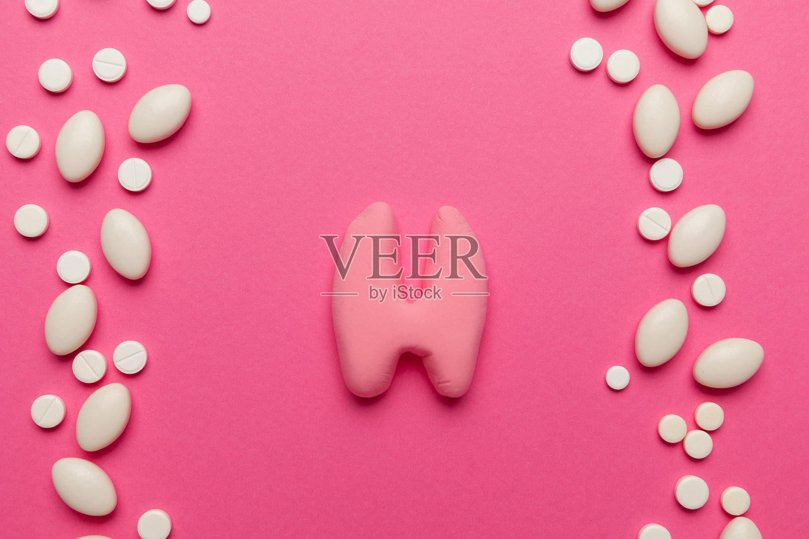 粉红色背景上的人类甲状腺。内分泌系统的治疗和预防。疾病和炎症的症状照片摄影图片