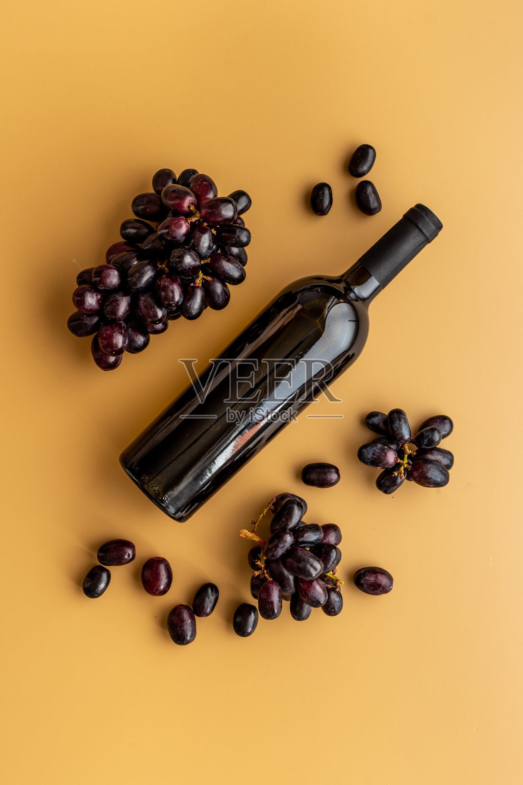 一瓶红葡萄酒配一串葡萄。俯视照片摄影图片