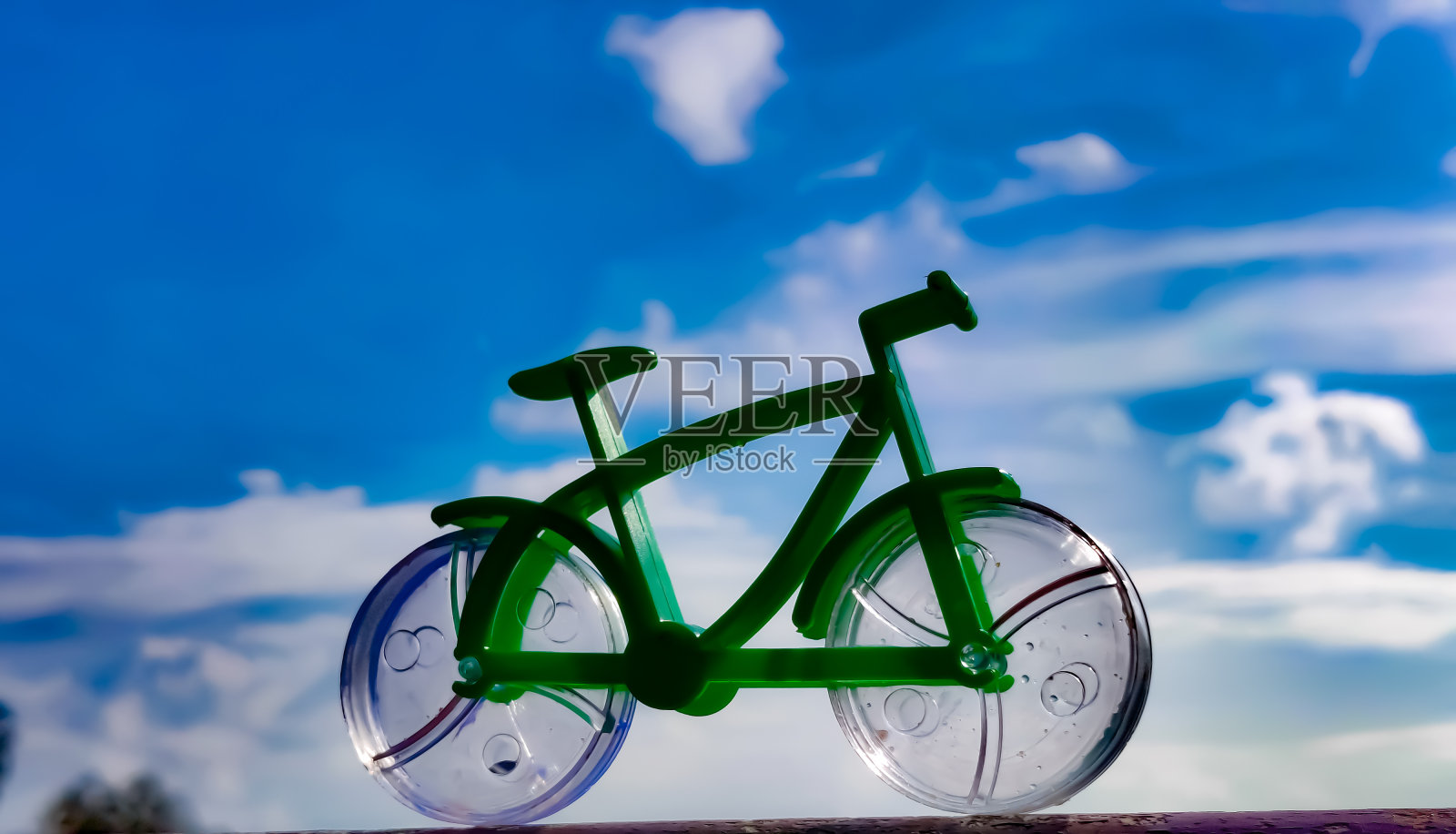 一个自行车玩具放置在表面多云的蓝天背景的惊人的观点。照片摄影图片