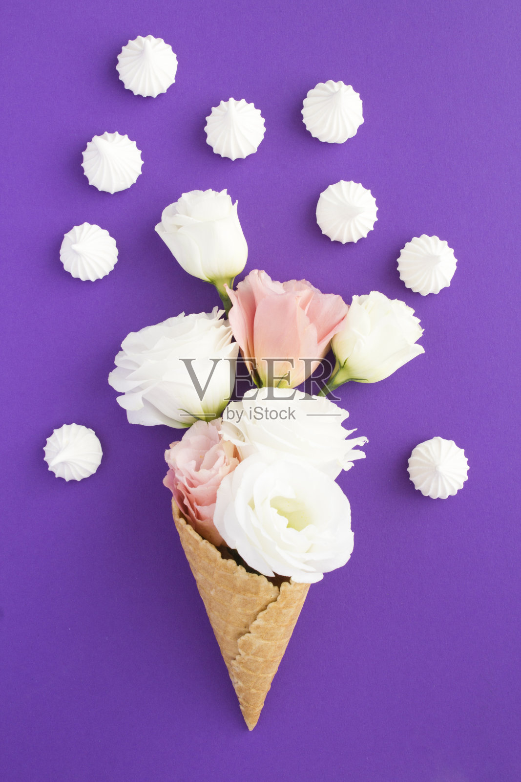 粉色和白色花朵的冰淇淋蛋筒，紫色背景上有白色蛋白霜照片摄影图片