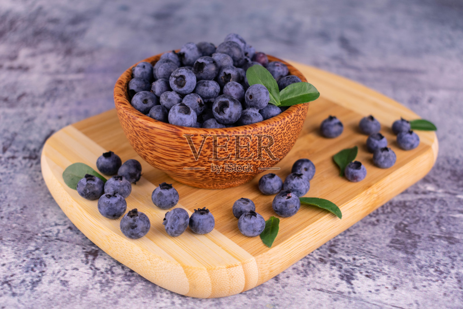 新鲜的蓝莓放在木板上的木碗里。照片摄影图片