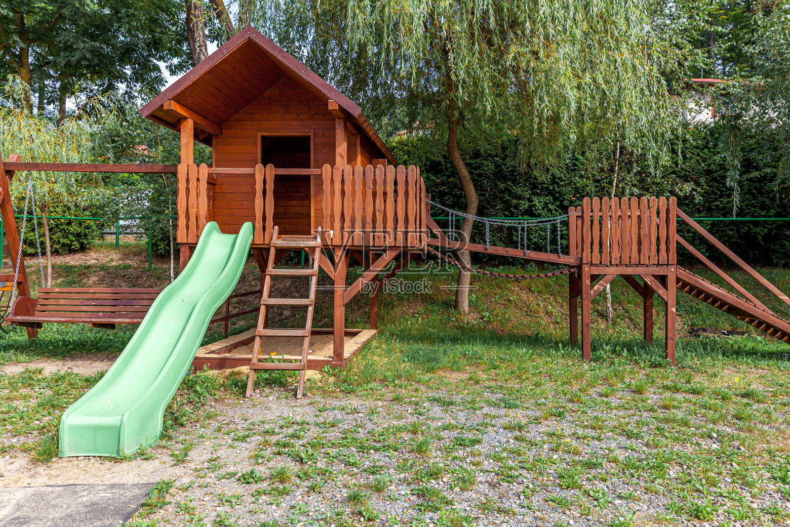 夏日里，空旷的现代木制儿童游乐场坐落在公园的绿色庭院里。好玩的玩具乐园。城市儿童户外锻炼活动。社区儿童的概念照片摄影图片