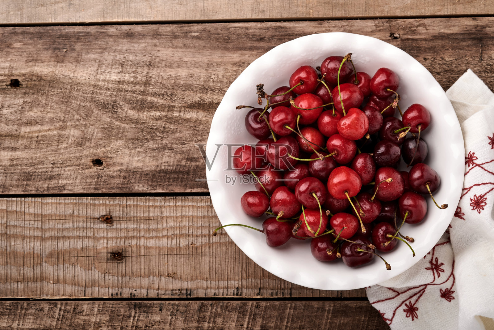 樱桃和水滴在白色碗在深棕色石头桌子。新鲜成熟的樱桃。甜蜜的红樱桃。前视图。乡村风格。水果的背景照片摄影图片