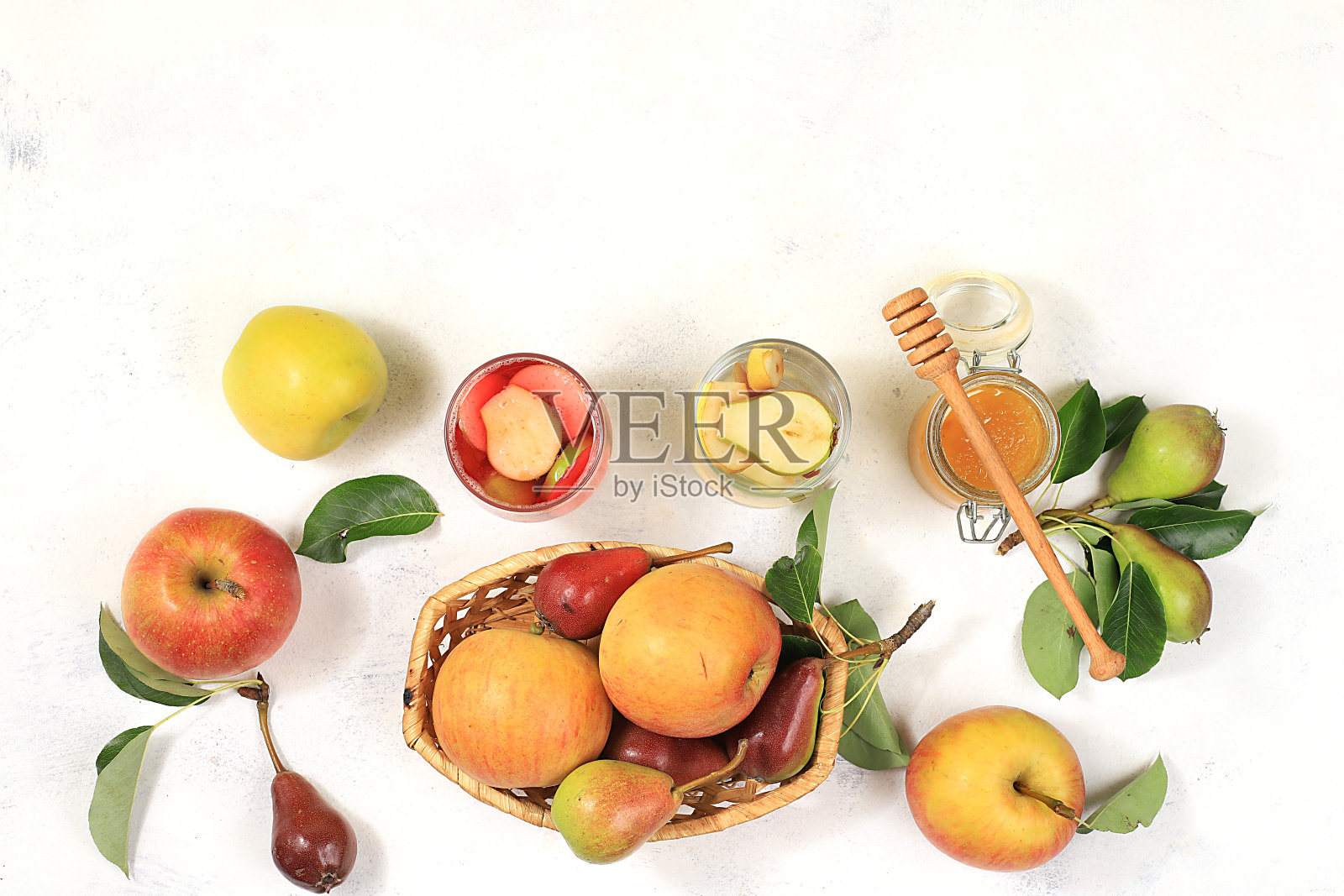 苹果和梨热葡萄酒与蜂蜜，苹果酒，果汁或果汁饮料在一个玻璃杯在阳光明媚的桌子上与新鲜梨和苹果在一个篮子。节食减肥的概念，在村里收获。健康饮食，身体排毒，选择性专注照片摄影图片