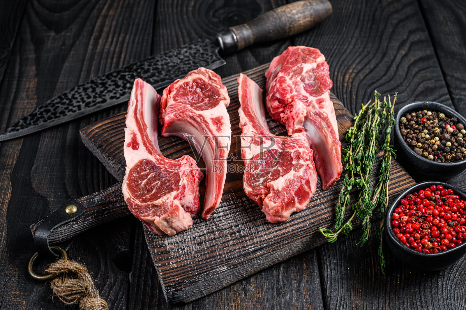 羊把生肉和骨头一起用盐、胡椒和香草切下来。黑色木制背景。俯视图照片摄影图片