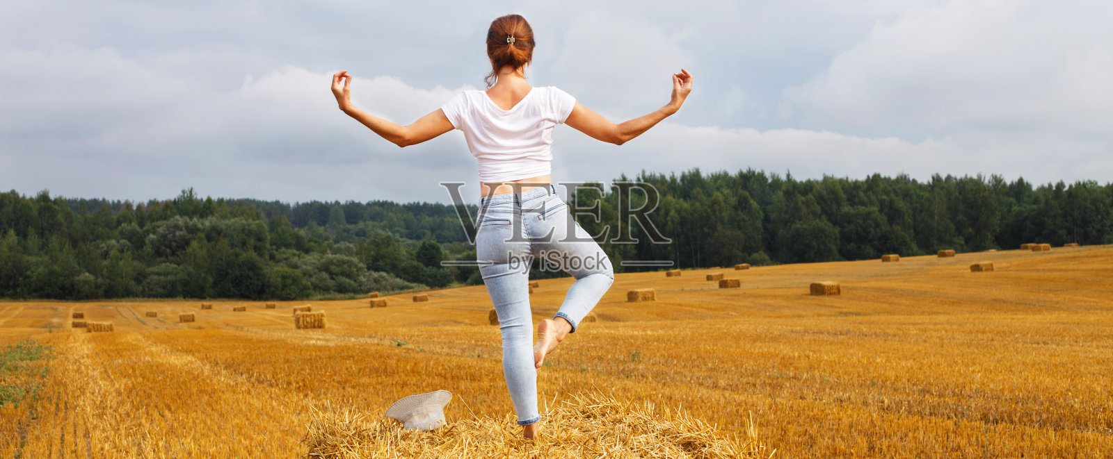 收割后，戴着草帽的女孩站在农用草堆上照片摄影图片