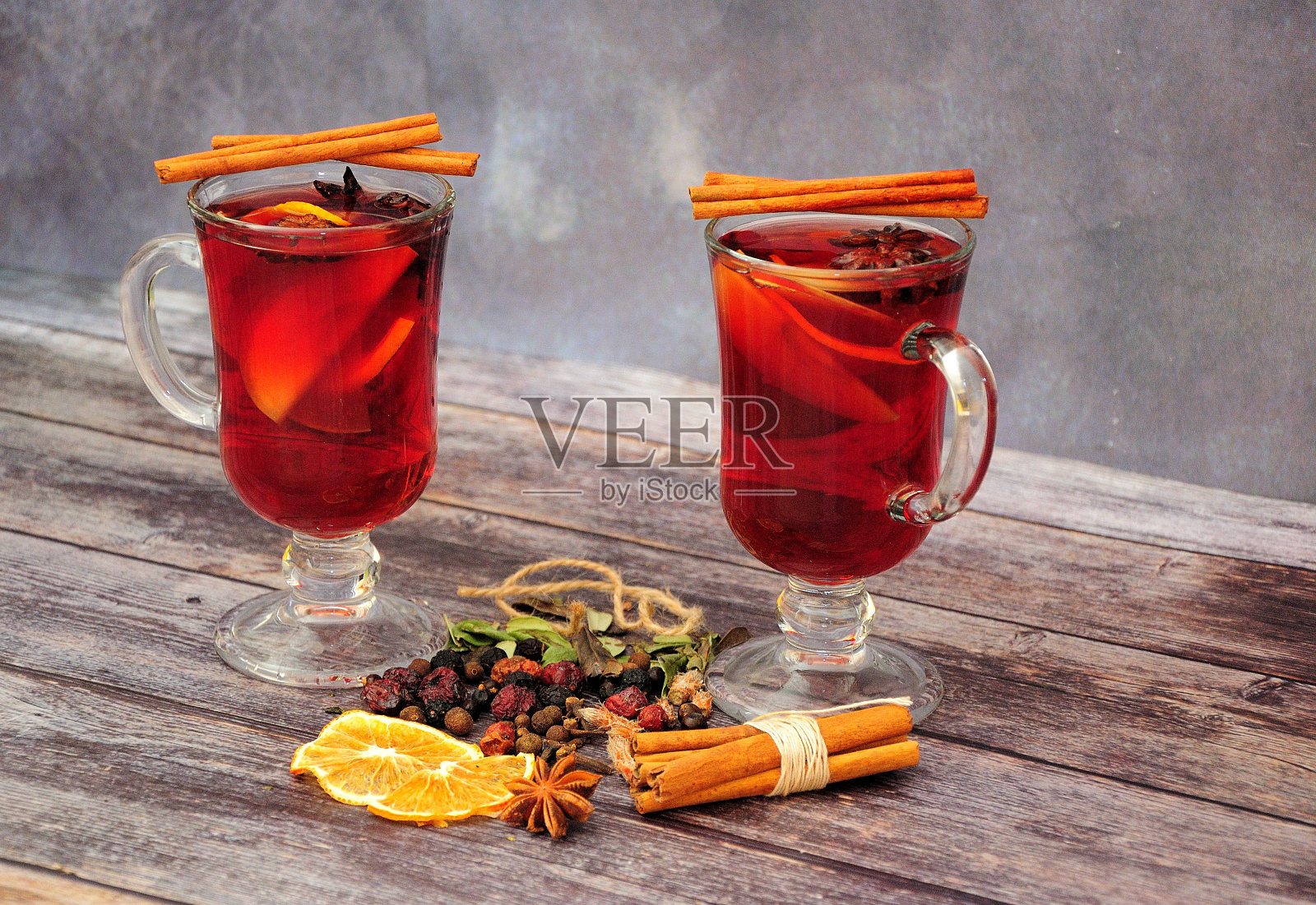 木桌上放着两杯热葡萄酒和一套香料。照片摄影图片